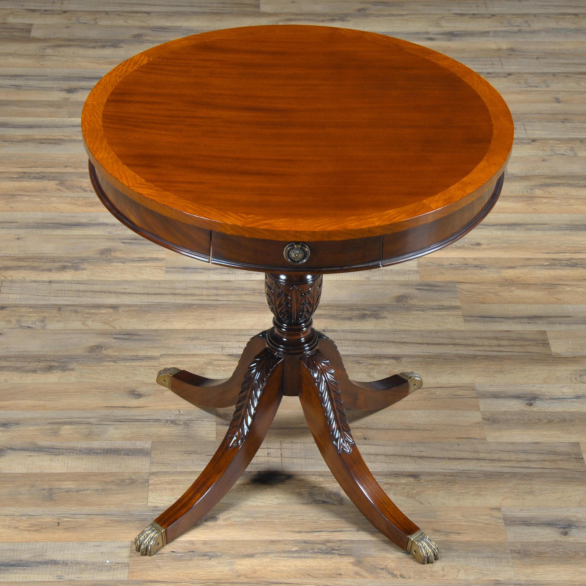 L'élégante et raffinée table tambour à un tiroir de Niagara Furniture est dotée d'une excellente quincaillerie, ainsi que d'un bord à bandes en bois satiné. La partie tambour de la table est fixée à une base en acajou massif, sculptée d'acanthes et