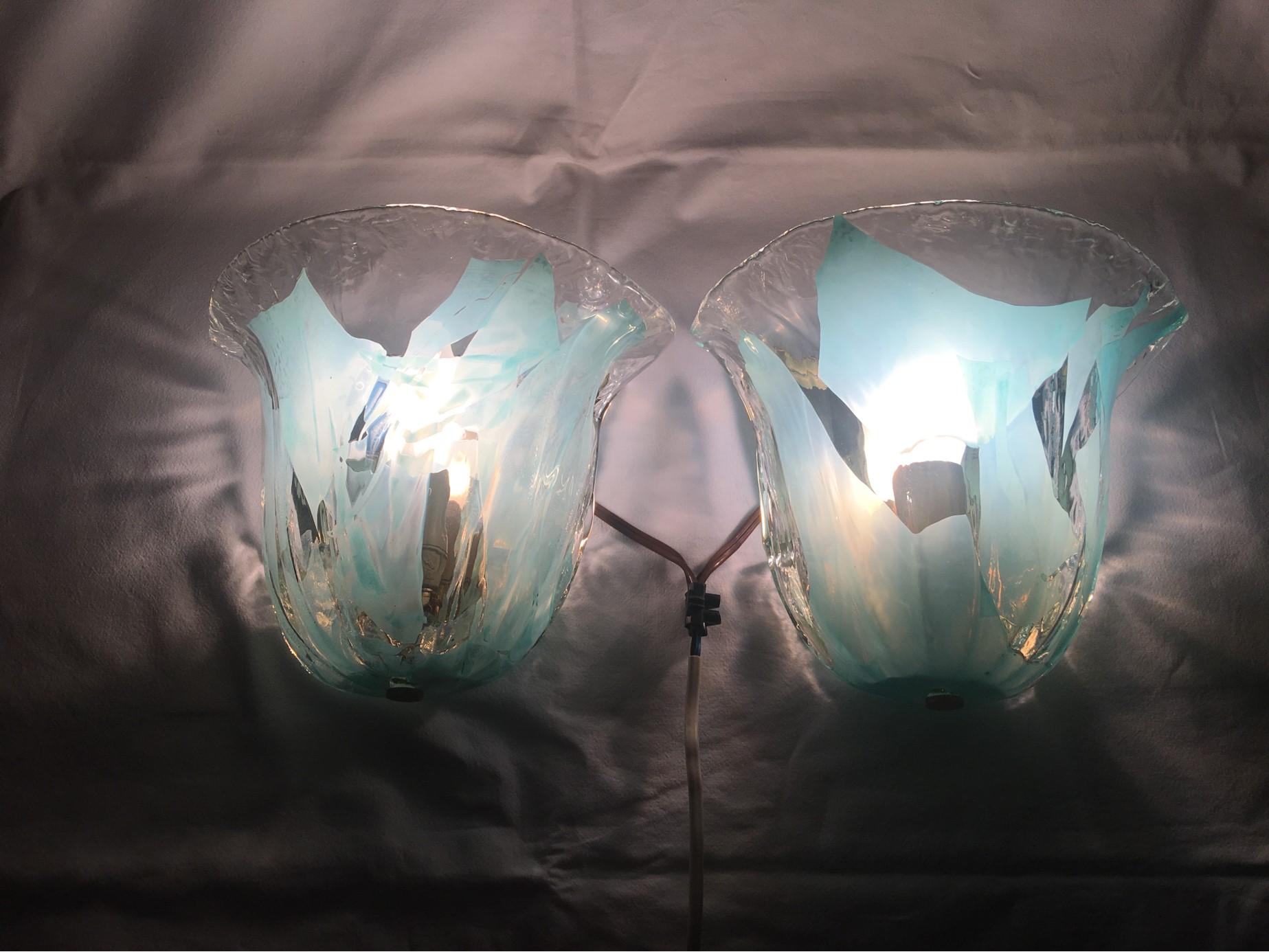 Rewired to meet US standards this lovely set of clear and turquoise glass sconces are an elegant addition to your home. Each fixture requires a European E 14 candelabra bulb with a max of 40 watts each. Very nice set. Shipped to you from Europe.