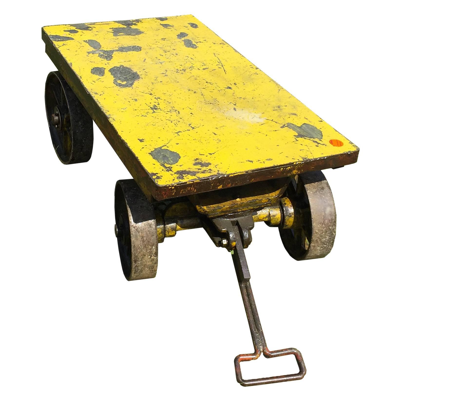 Iron and cast iron Industrial wheelbarrow, rectangular shape, with 4 big wheels (11” diameter) and a long handle that allows the front wheels to rotate, North America, 1900. The top shelf has a thickness of 4 inches.