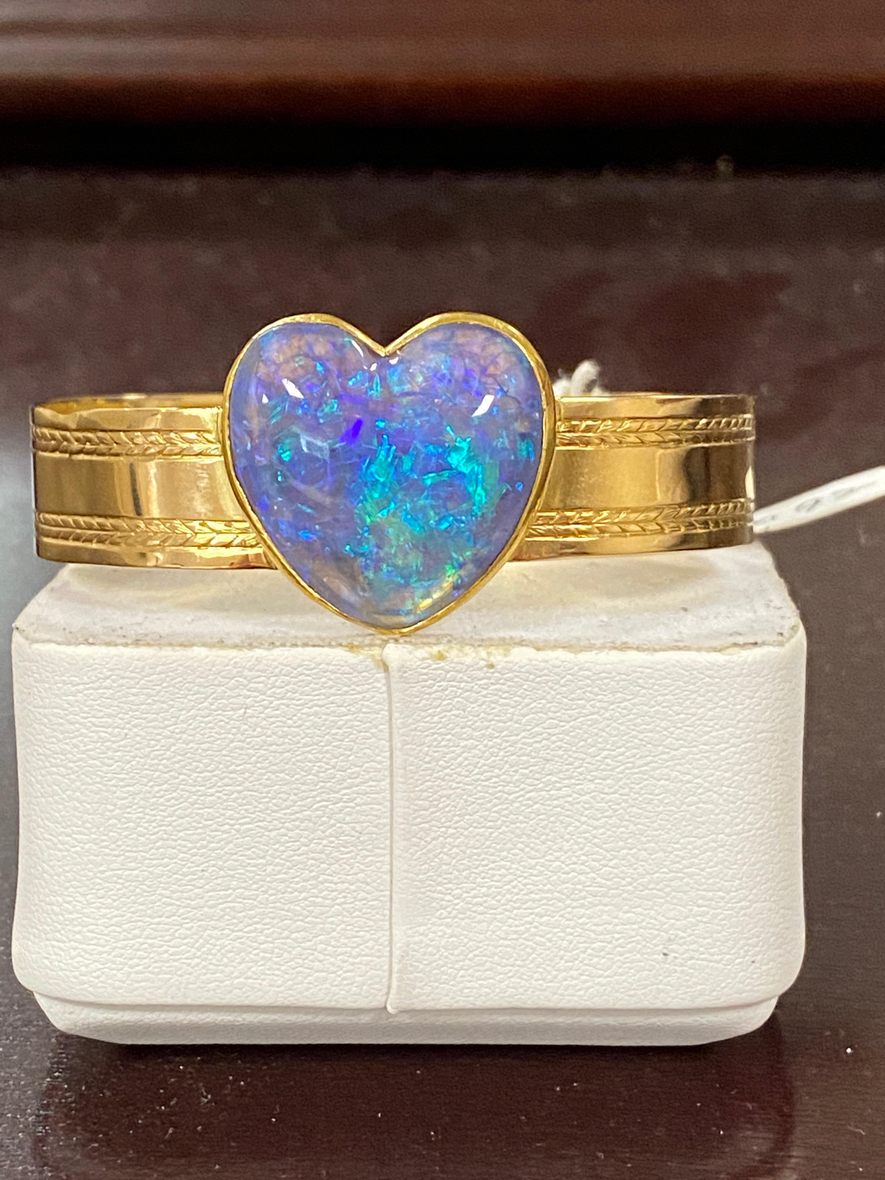 One lady's black opal and diamonds bracelet in 14k yellow gold. Base color is semi black and fire color includes blue/green.  Saturation scale is average with PinFire pattern color. Bright opal with cabochon and heart shape. Measurements include