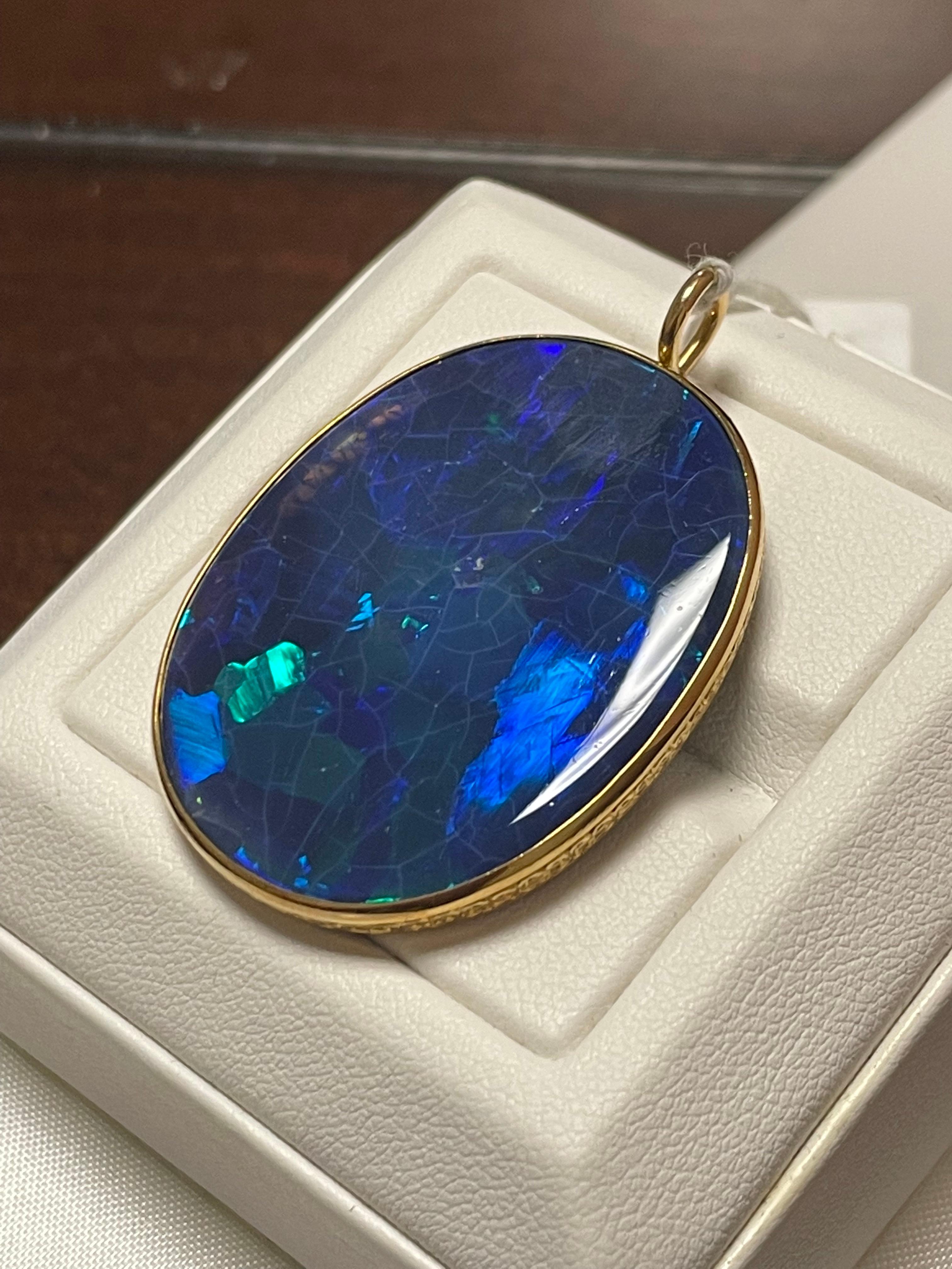 One lady's Marcus & CO black opal with fire color of purple/green.  Saturation scale is vivid with a flash fire pattern.  Opal is round, and cabochon.  Measurements are 37.0 x 20.0 mm. Weight is 12 carats. Pendant is cast and hand assembled with 18k