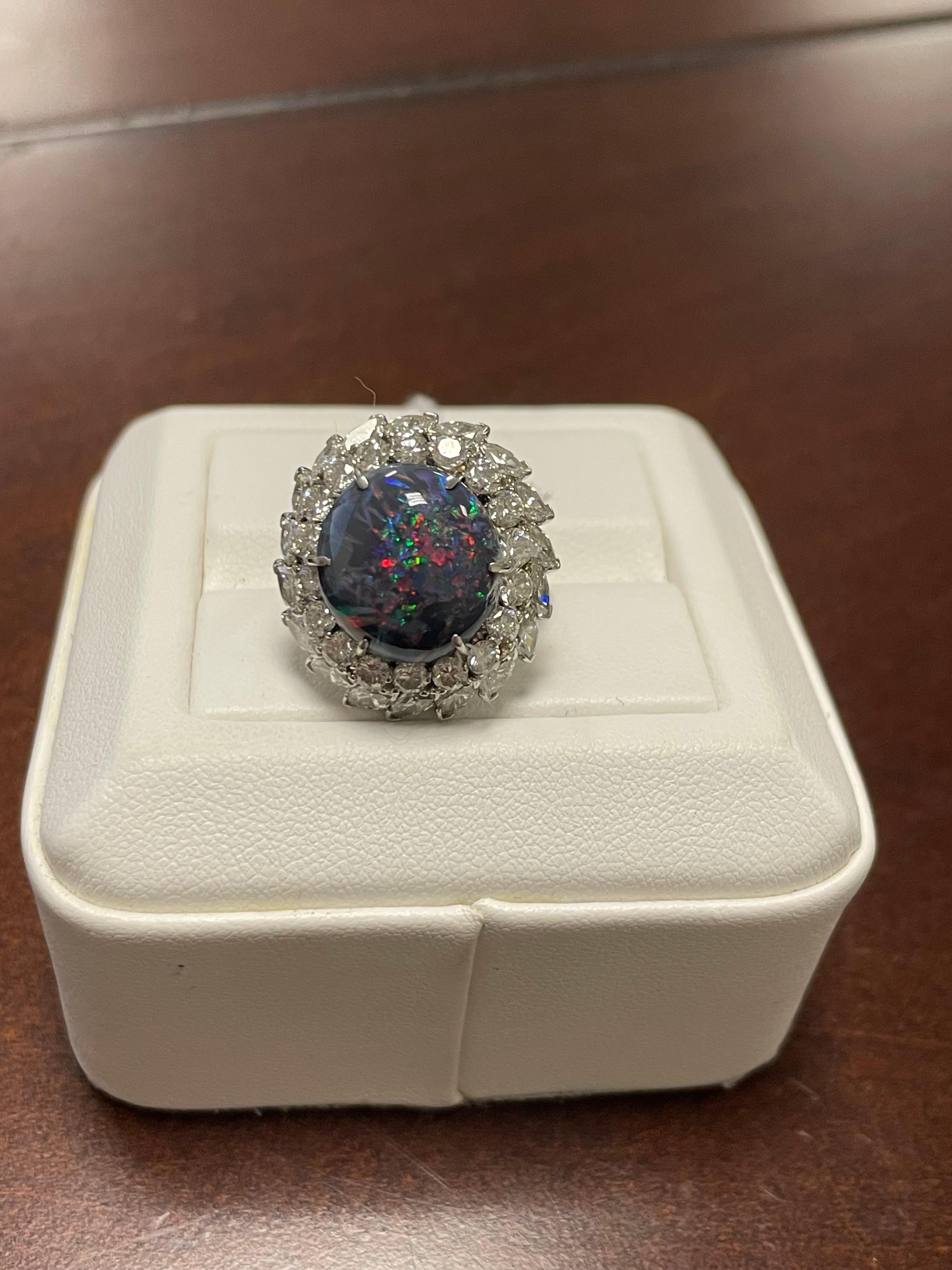 One lady's opal and engagement ring in platinum.  Black opal has multicolor fire color with average saturation scale.  Bright PinFire patter with round cabochon shape.  Measurements of diamonds is 4.5 mm x 2.5 mm with 4.15 carats.  Piece includes GH