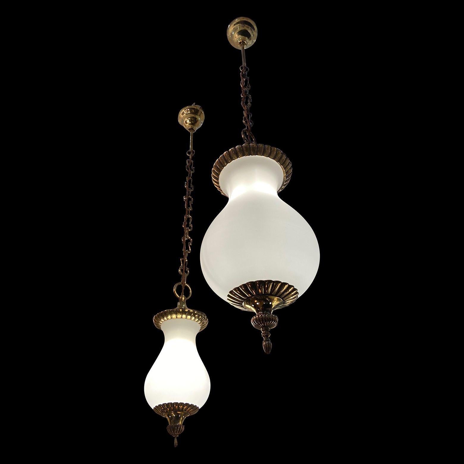 One large and one small glass and brass lanterns or pendant lights, sold as a pair. 
the brass is heavy and beautifully crafted.
Dimensions posted are of the large one.
The small one is 108cm (42 inches) long x 15cm ( 6 inches) diameter.
Chain could