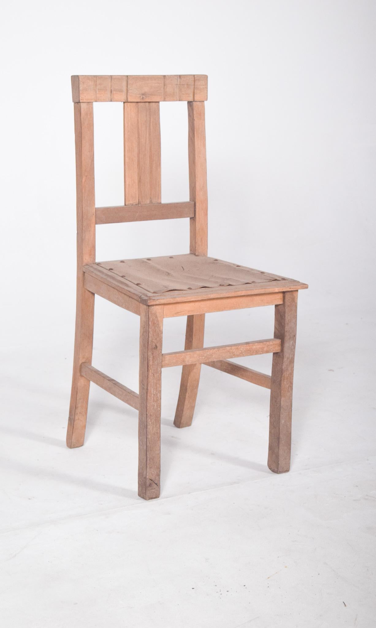 Light wood chair. With a simple and robust structure in solid wood, the backrest is composed of a vertical central board and an upper crossbar with straight decorative carvings. The seat is flat, made of boards joined by exposed nails, without