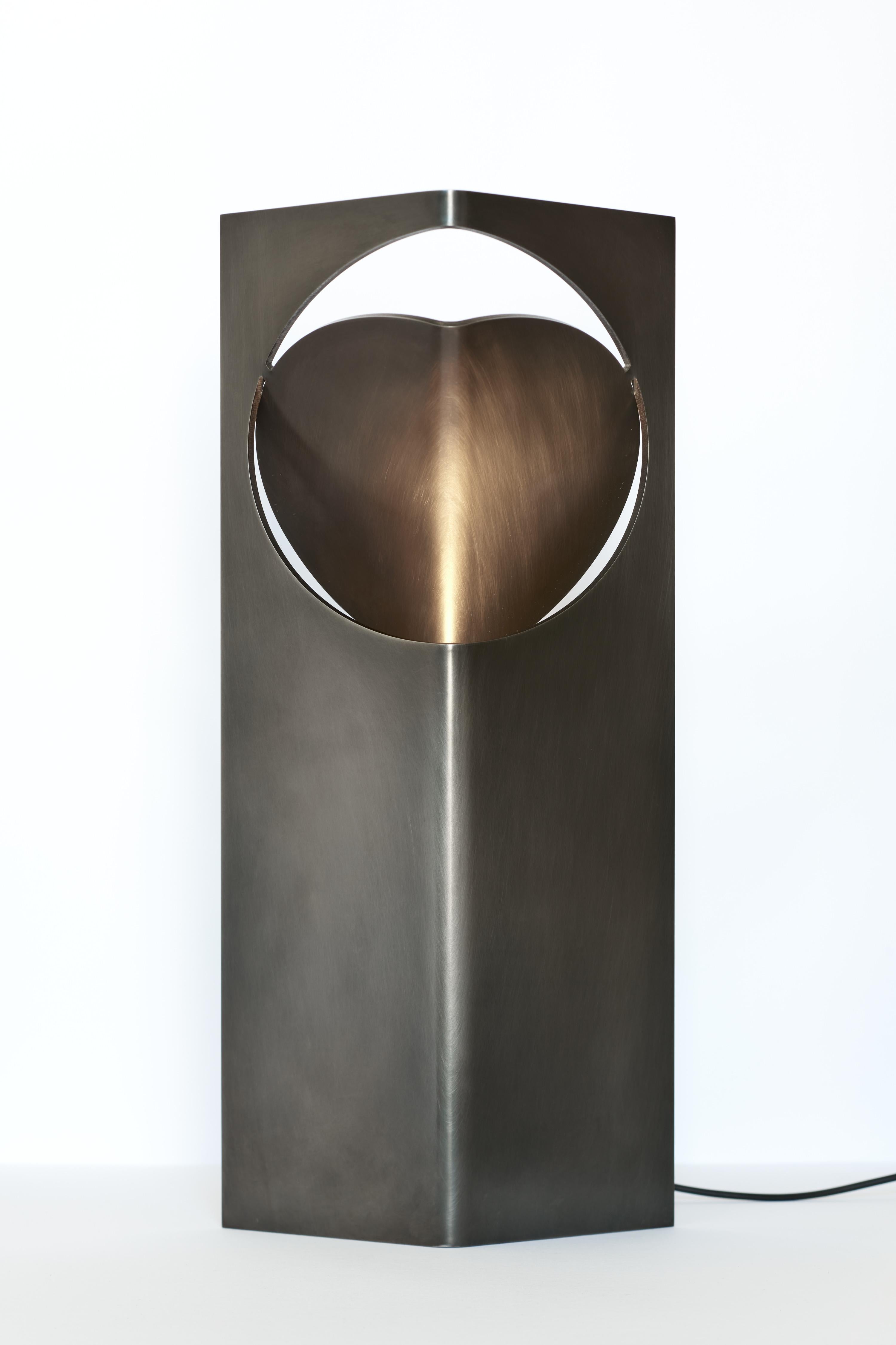 La colección ONE Table Light de Frank Penders es una serie de lámparas que combinan una ingeniosa simplicidad de formas con una riqueza de luz y textura de materiales. Con un diseño de acero inoxidable cepillado a mano, esta lámpara de mesa es el