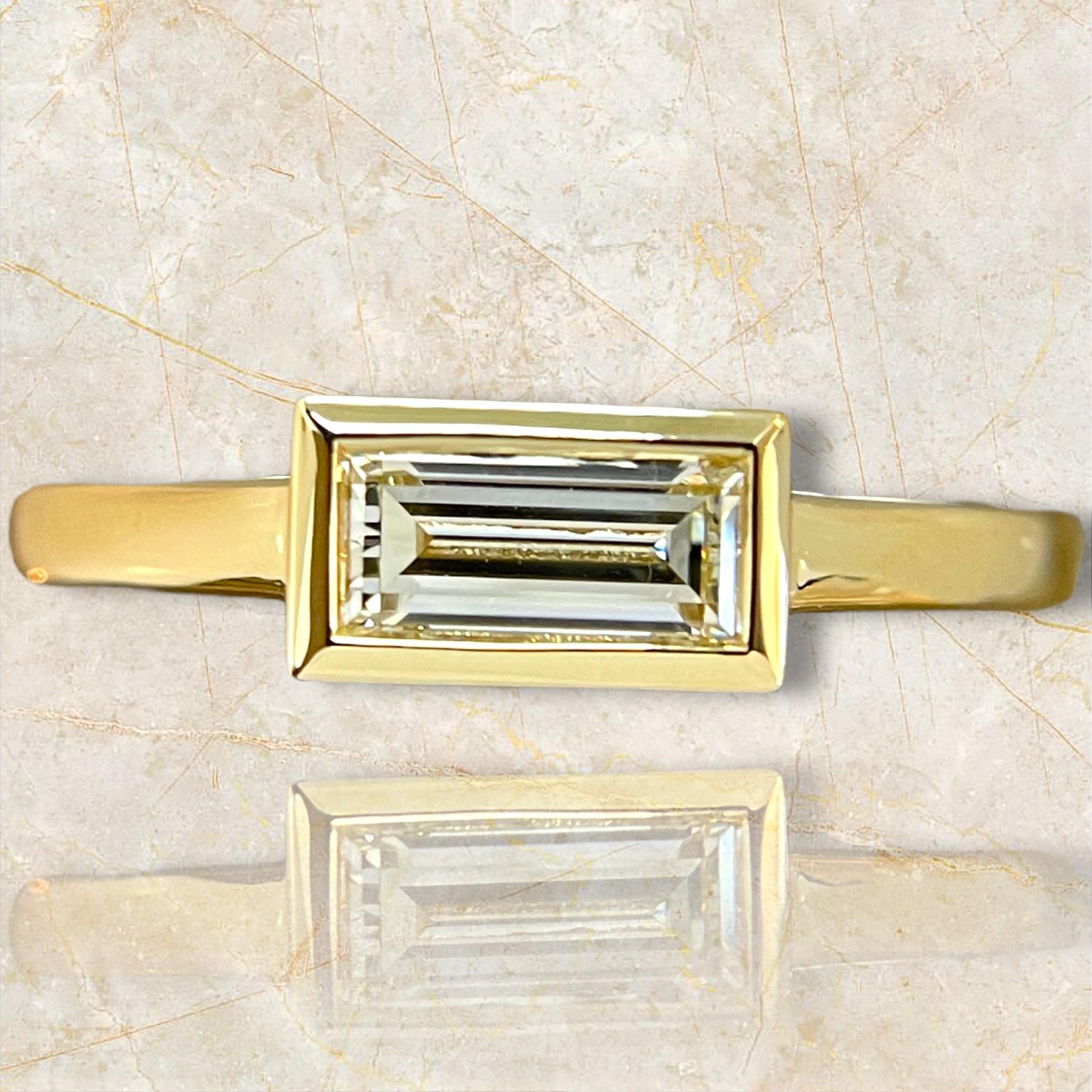 Adorn yourself with the exclusive radiance of this limited edition 18K yellow gold ring, showcasing a beautifully bezel-set baguette diamond. The luxurious gold setting complements the diamond's unique cut, creating a piece that exudes