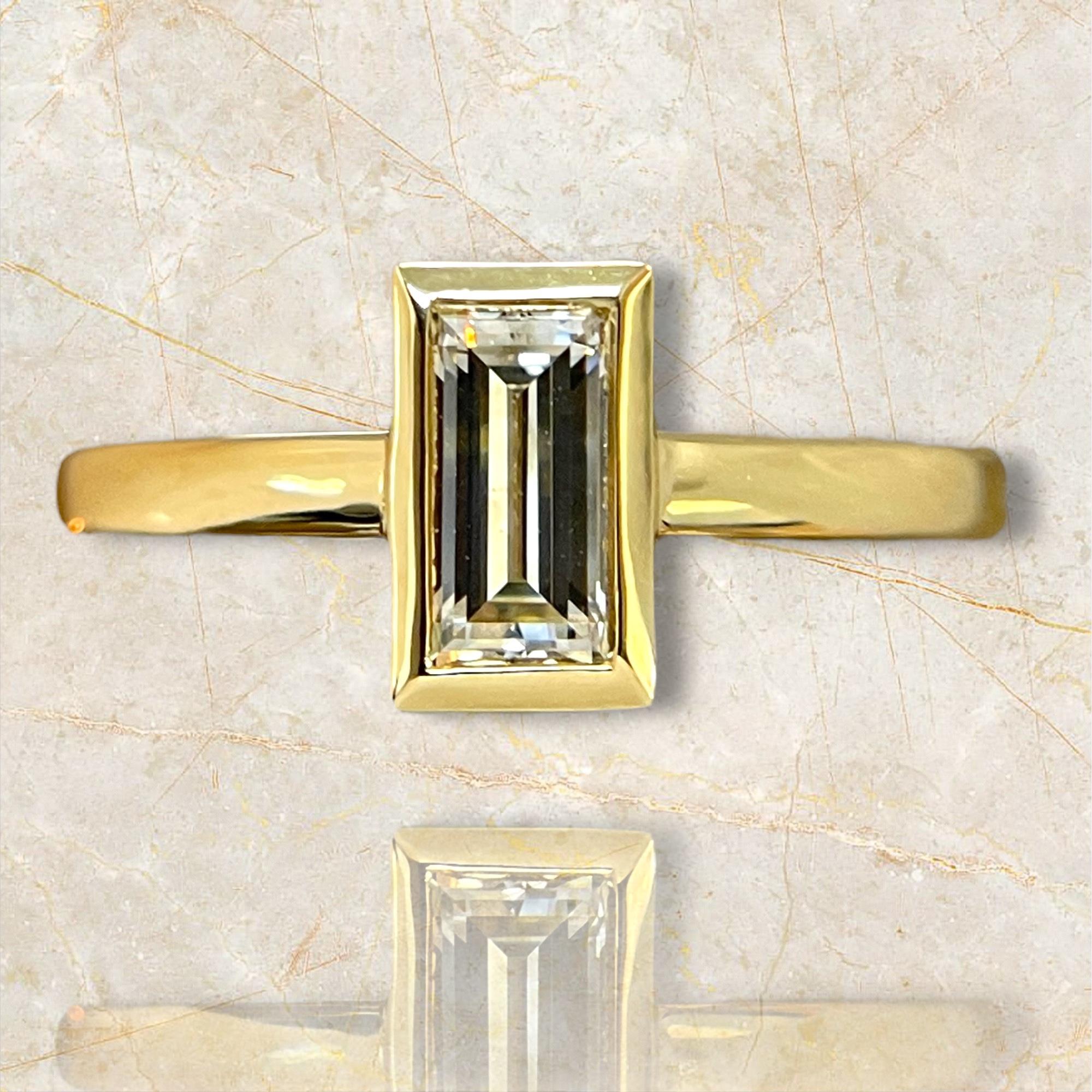 Adorn yourself with the exclusive radiance of this limited edition 18K yellow gold ring, showcasing a beautifully bezel-set baguette diamond. The luxurious gold setting complements the diamond's unique cut, creating a piece that exudes