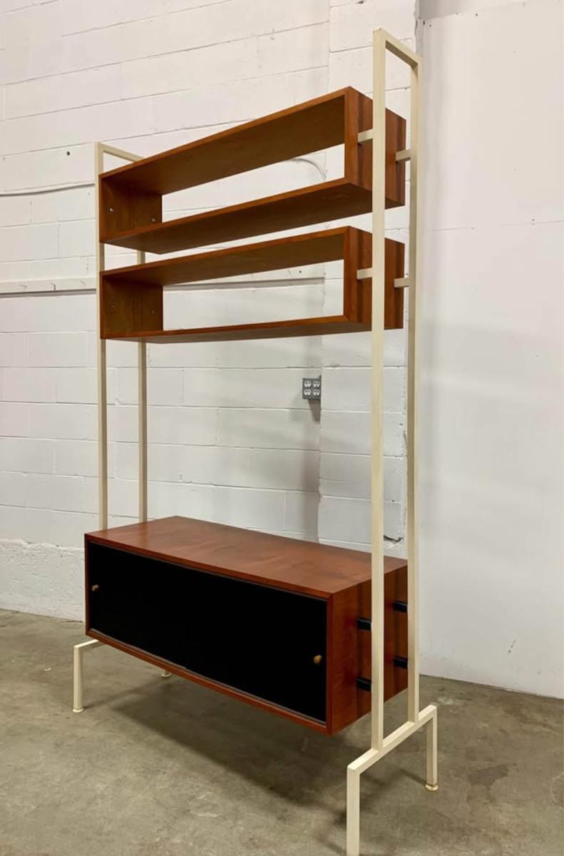 A rare and architectural 1960s Danish wall unit that perfectly balances form and function. Crafted from warm teak and powder-coated steel, this freestanding piece is as much a sculptural statement as it is a highly functional storage