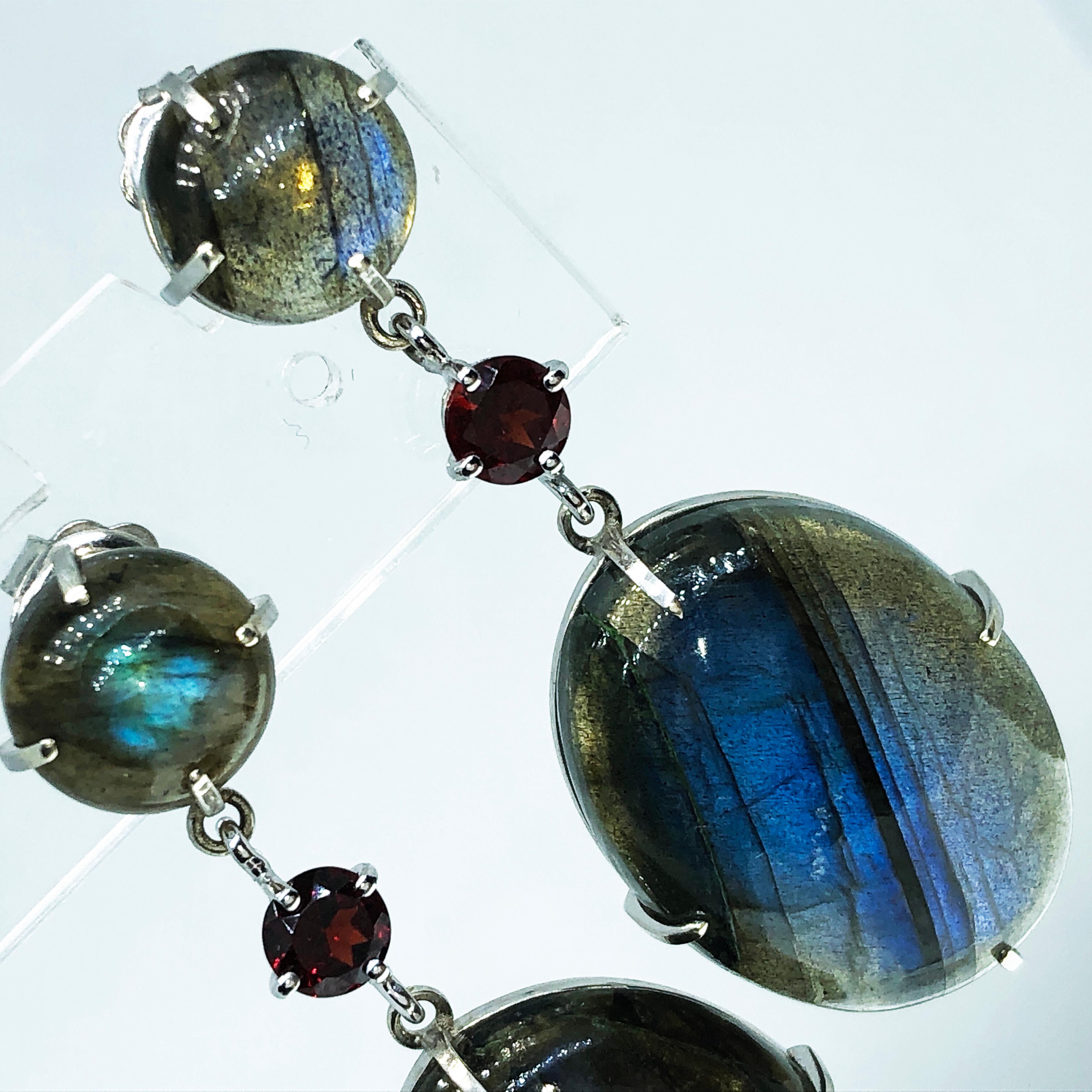 One-of-a-kind  Contemporary  Dangle Earrings Featuring 0.12Carat Round Red Garnet and 53.50 Carat Oval(0.911x0.666in) and Round Cabochon Natural Peacock-Blue Labradorite in a 9Kt White Gold  Setting.
The color-changing of the Labradorite's Cabochon