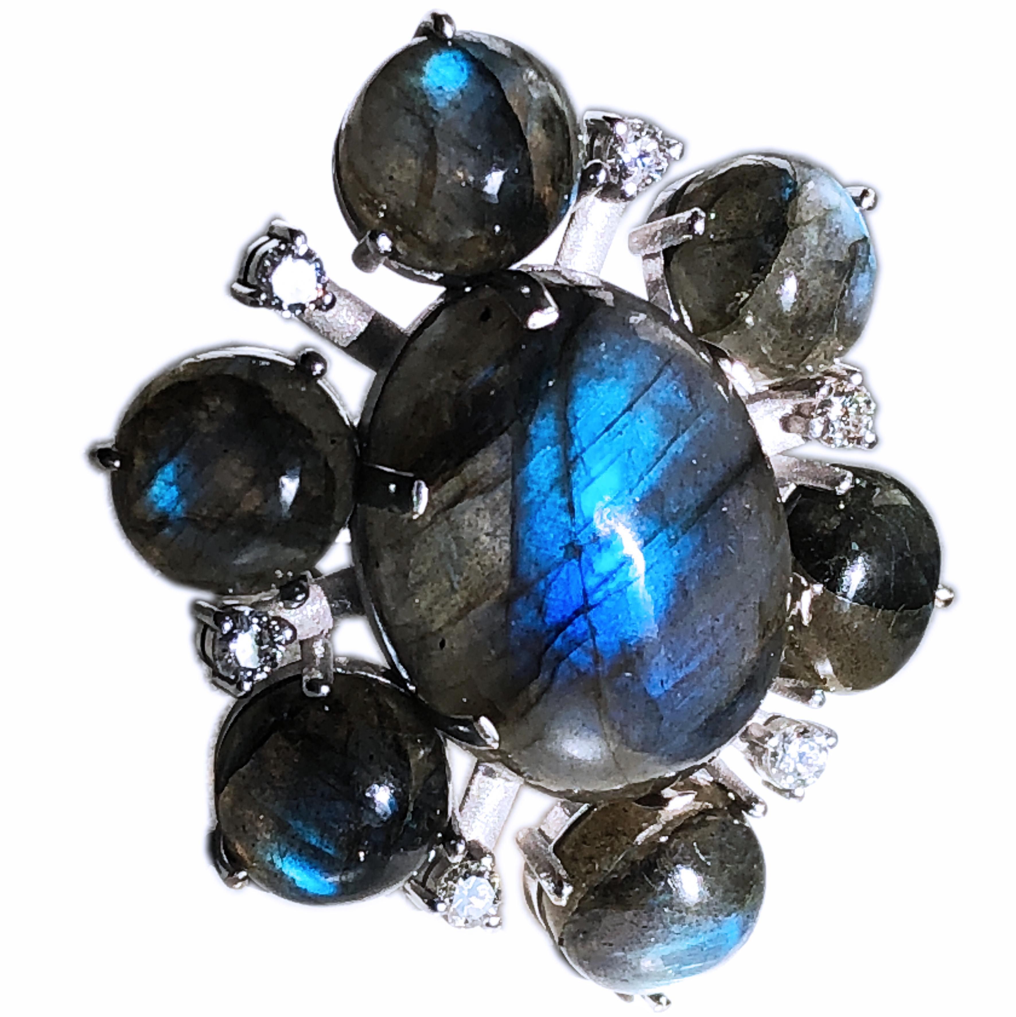 One-of-a-kind Contemporary Cocktail Ring Featuring a 22.50 Carat Natural Oval Labradorite Cabochon (0.911x0.666in) surrounded by six White Diamond(0.61Kt) and six round small Labradorite Cabochon in a 15.80g 18K White Gold Setting.
The incredible