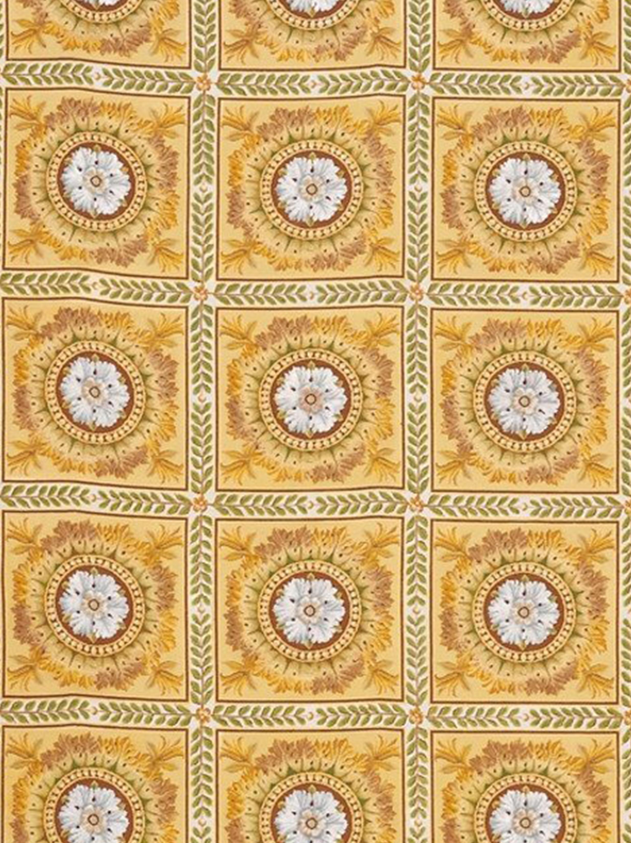 Inspired by the rugs of the French Empire period, a circular arrangement of leaves in green, russet and gold surround white, pale blue and beige rosettes on a warm yellow and gold background within a sienna red border. Made with fine quality wool