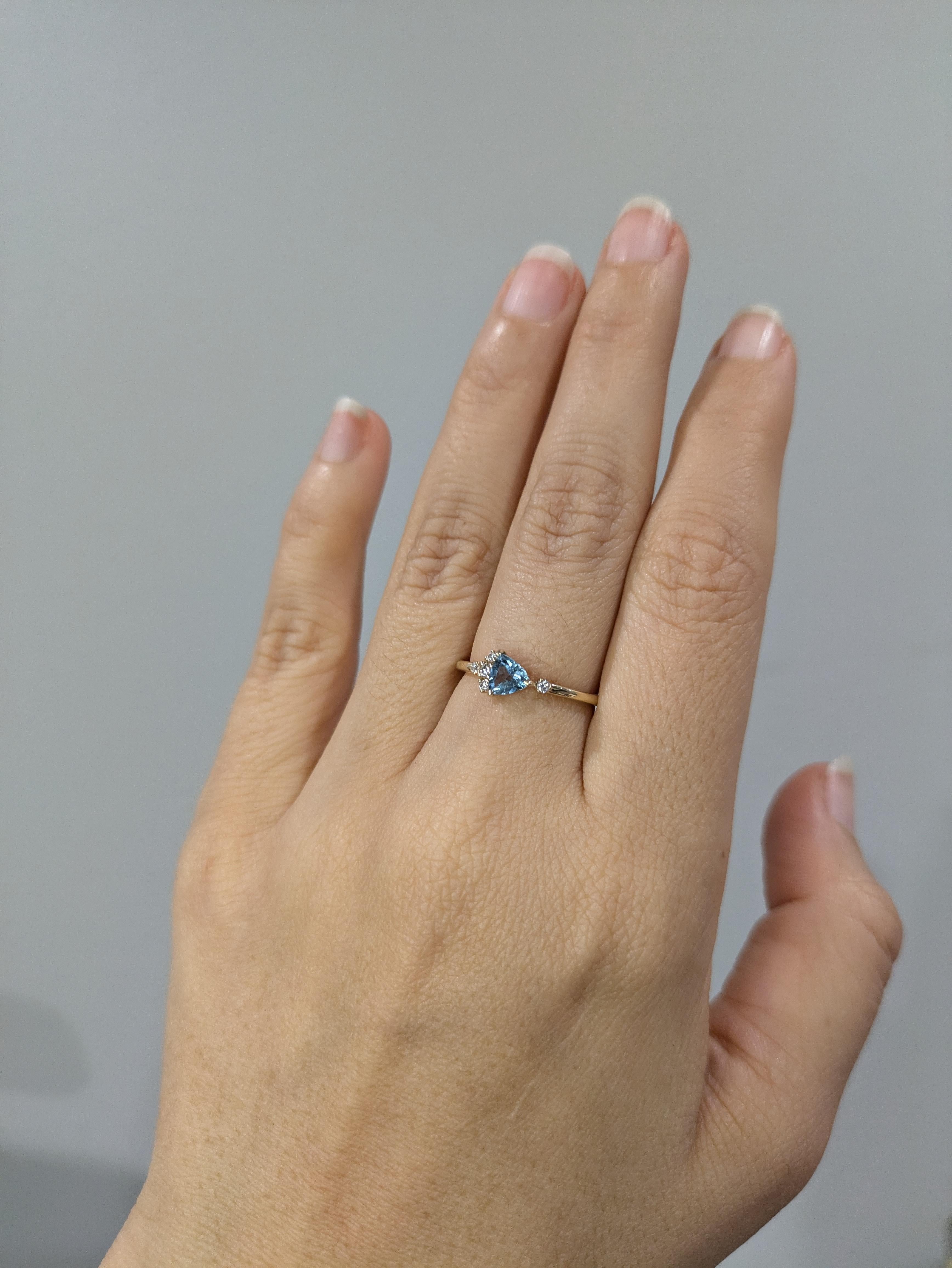 Ein bezaubernder, zierlicher Ring mit einem 0,34 Karat schweren Trillion-Aquamarin in der Mitte, akzentuiert mit Diamanten aus ethischen Quellen, die in der Erde abgebaut werden. Dieser Ring aus massivem 14-karätigem Echtgold verbindet zeitlose