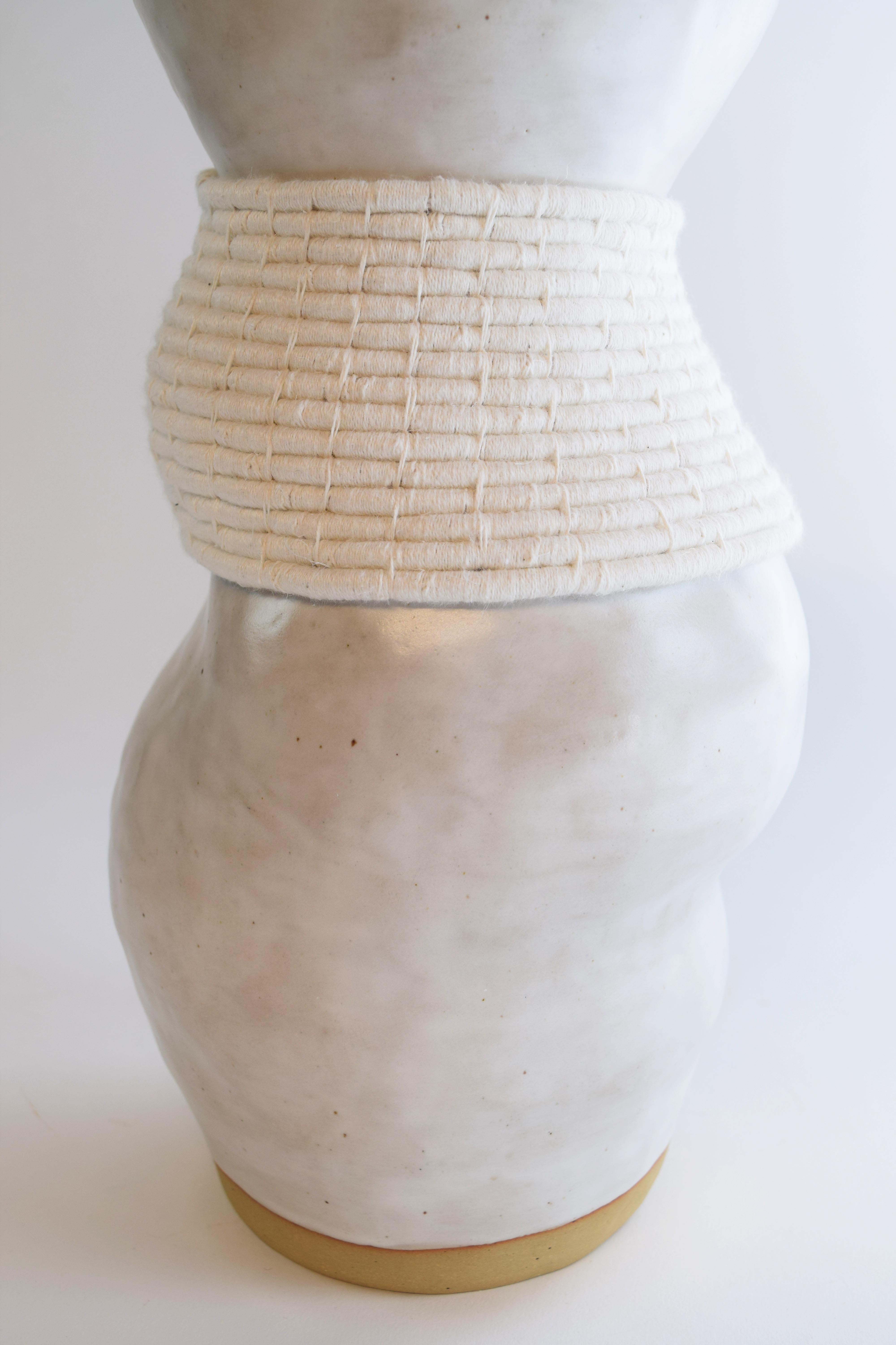 Hand formed asymmetrical stoneware vessel with satin white glaze. Woven white cotton detailing around the outside. The vase is asymmetrical so each view will be different. Vase is water tight.

Measures: 11.5”H x 6”W

One of a kind collections