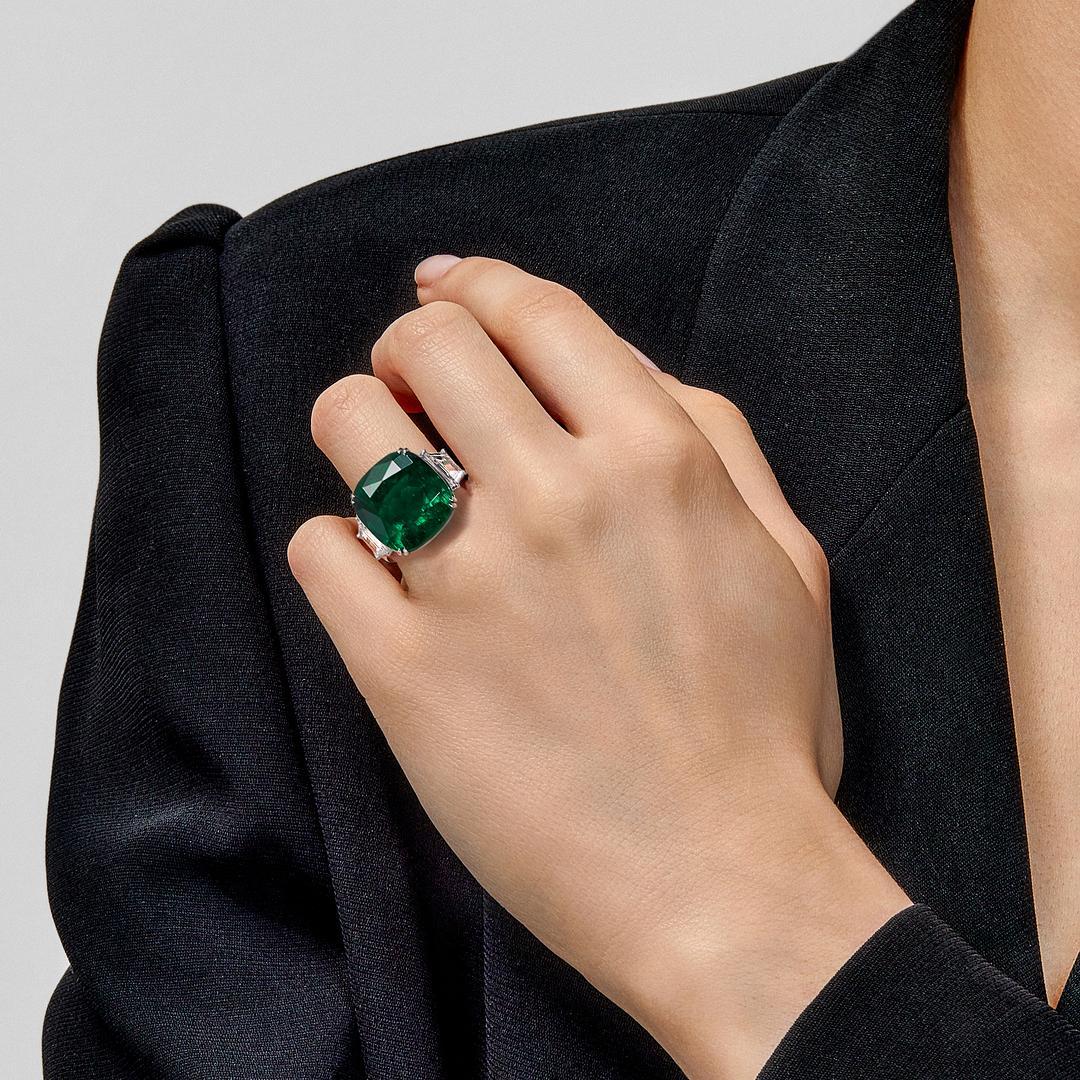 Featuring a 17.20-carat modified-brilliant cut cushion-shaped Colombian emerald, this one-of-a-kind ring will become the most prized piece in your fine jewelry collection. The exquisite emerald is flanked by sparkling trapezoid-cut diamonds weighing