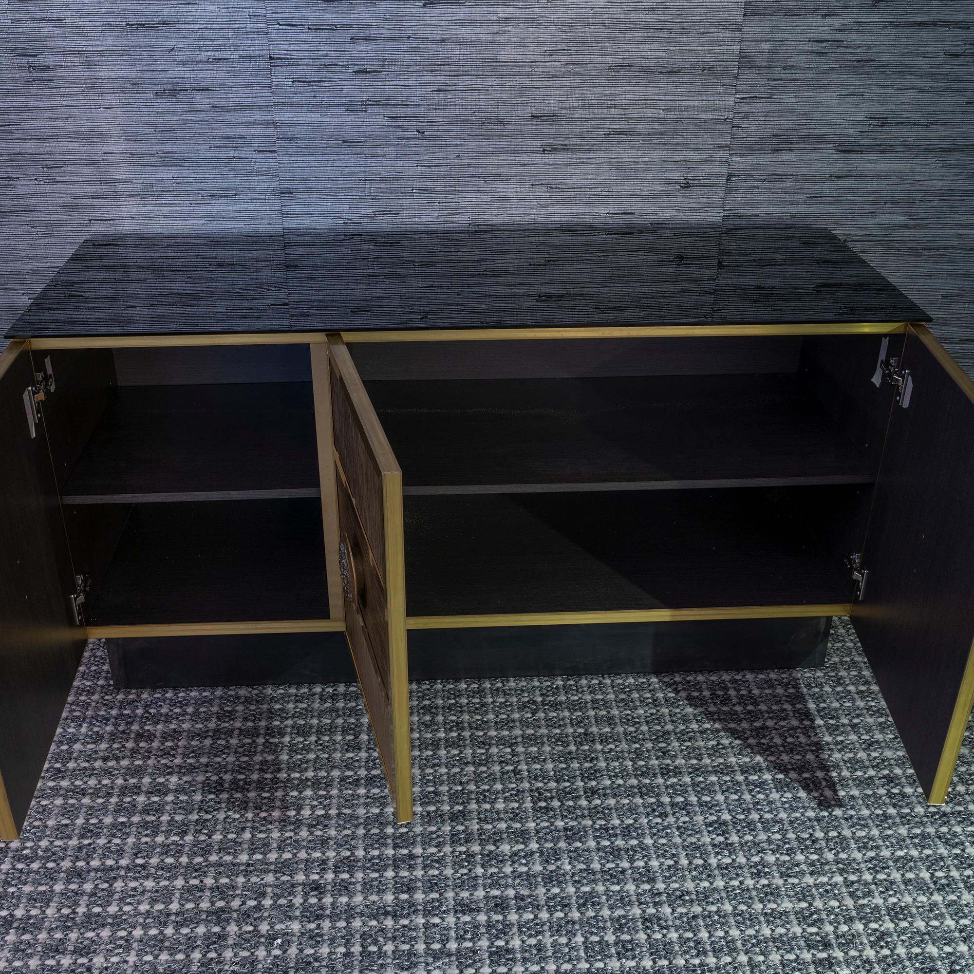 One of a kind three doors sideboard, covered with natural and patined brass wire applied vertically and horizontally as to create a geometrical design, interior in grey laminate, top in black painted glass with vintage patina, natural raw steel