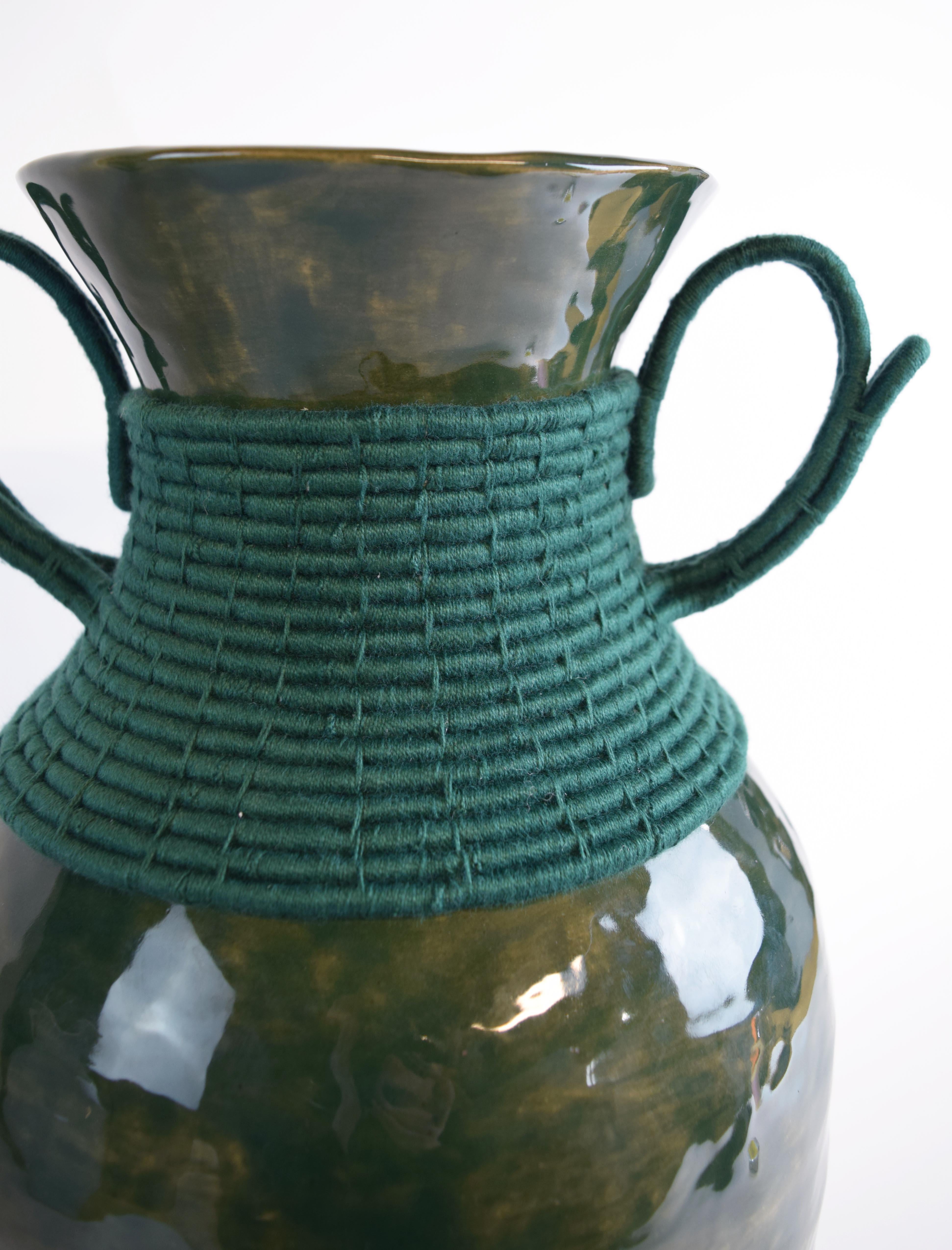 Hand formed stoneware vase with green glaze. Woven green cotton detailing around the outside. The inside of the vase is left unglazed, not recommended to hold flowers.

18.5”H x 10”W

One of a kind collections with a limited number of pieces are