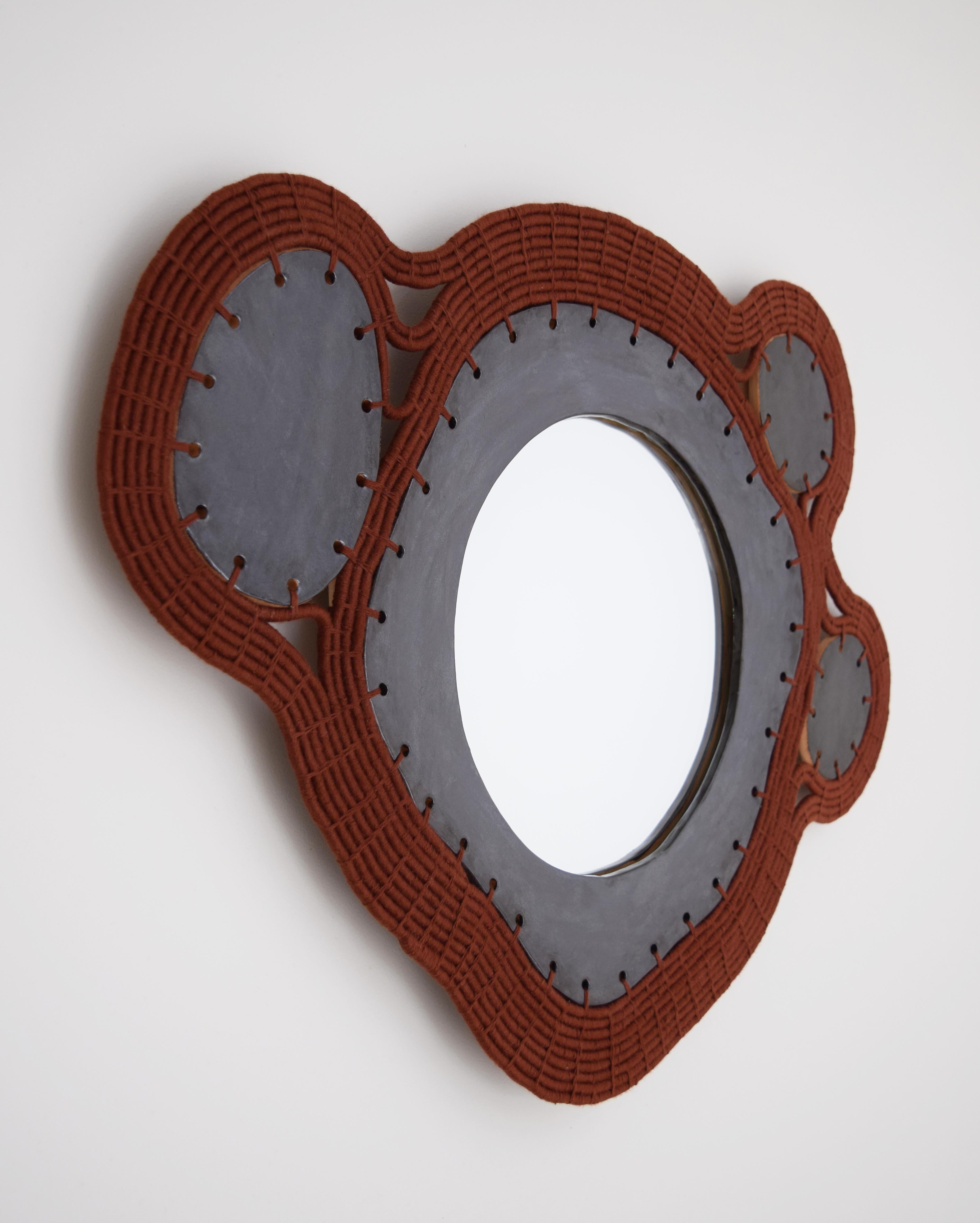 Mirror #794 by Karen Gayle Tinney.

One of a kind - available without a lead time.

Mirror with a hand formed stoneware frame glazed black. Woven rusty brown cotton exterior frame with inlaid ceramic panels. Black felt backing on mirror with hanging