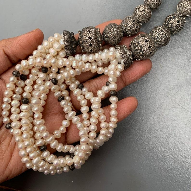 Una collana di grande effetto con antiche perle filigranate in stile etrusco in argento sterling, intervallate da fili di perle coltivate d'acqua dolce. Questa collana mostra un'armoniosa fusione di antiche tecniche di lavorazione dell'argento con