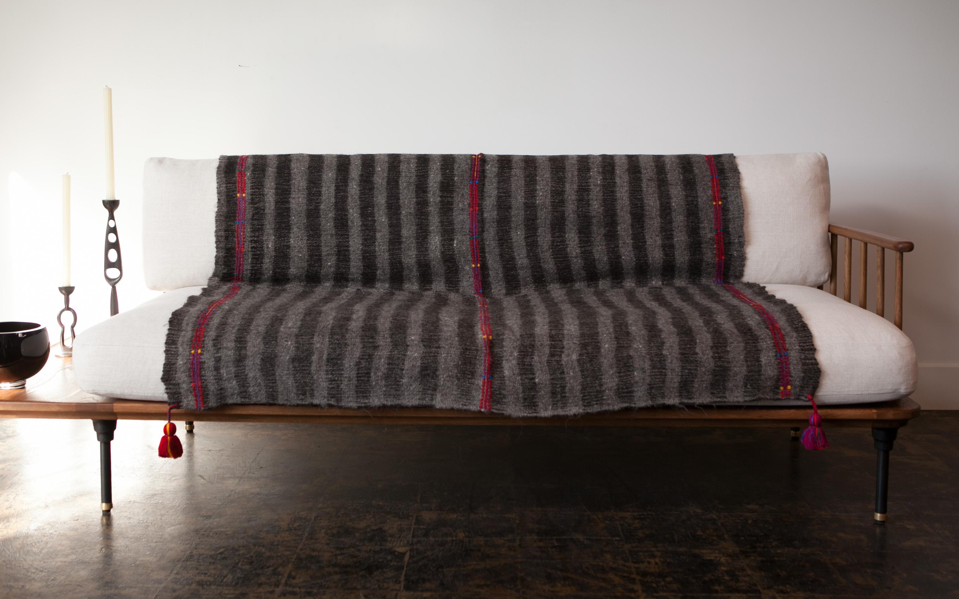 Handwoven on backstrap looms in Chamula, Chiapas, the textile of this delightful throw is made 100% from wool sheared from Chamula community sheep, considered sacred in local culture, embroidered and decorated with red pompoms dyed with cochineal.
