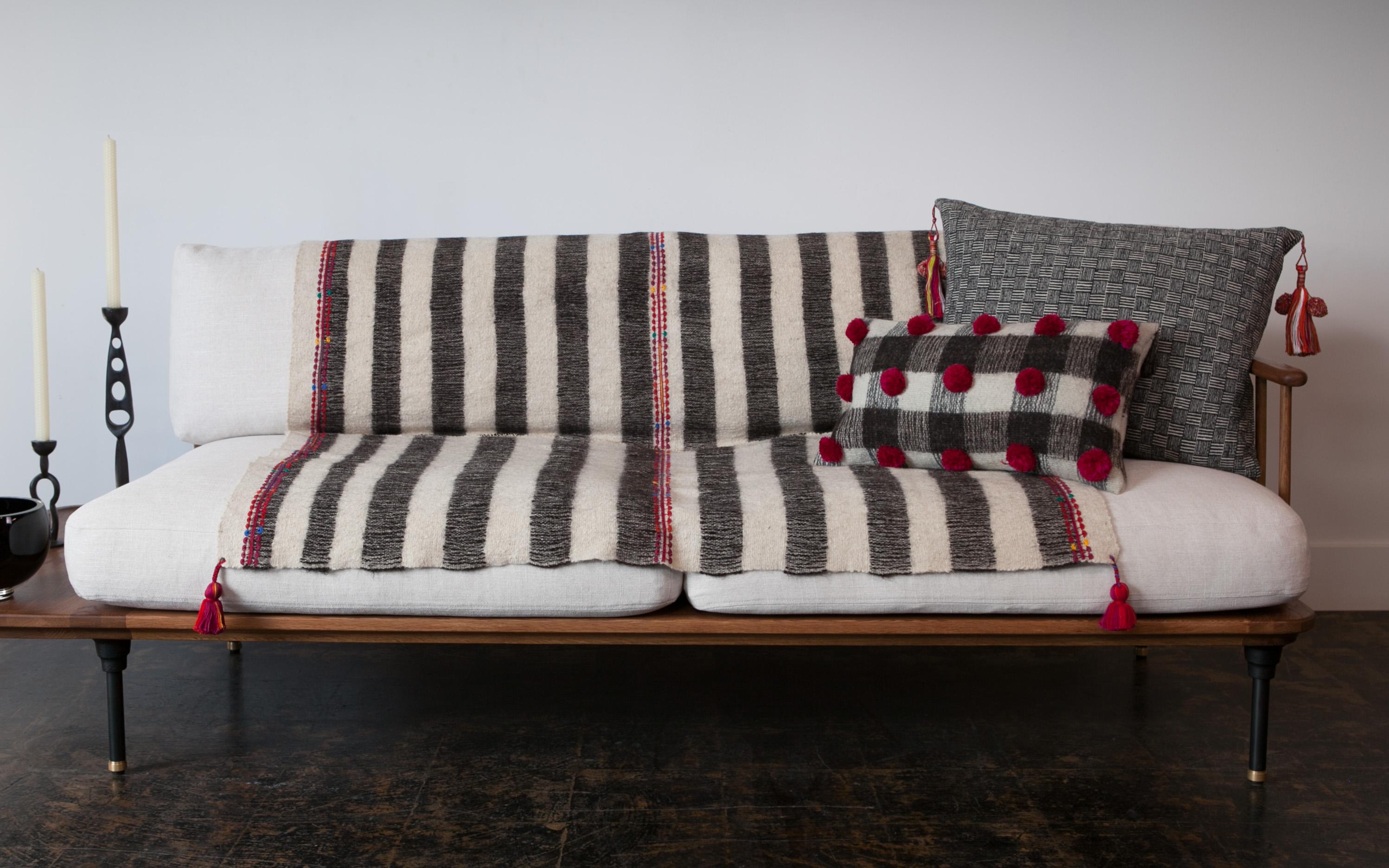 Handwoven on backstrap looms in Chamula, Chiapas, the textile of this delightful throw is made 100% from wool sheared from Chamula Community sheep, considered sacred in local culture, embroidered and decorated with red pompoms dyed with cochineal.