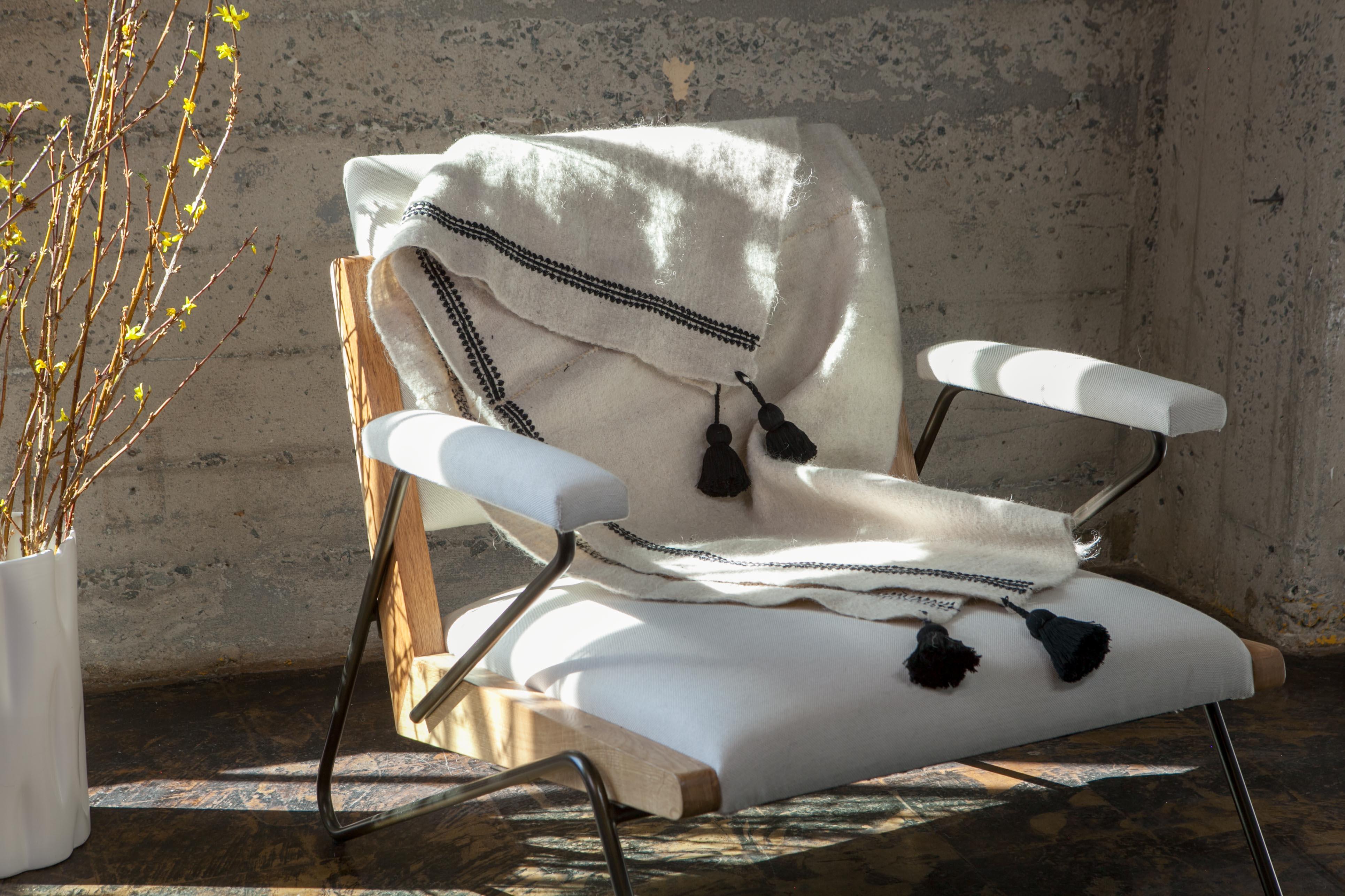 Handwoven on backstrap looms in Chamula, Chiapas, the textile of this delightful throw is made 100% from wool sheared from Chamula community sheep, considered sacred in local culture, embroidered and decorated with red pompoms dyed with cochineal.