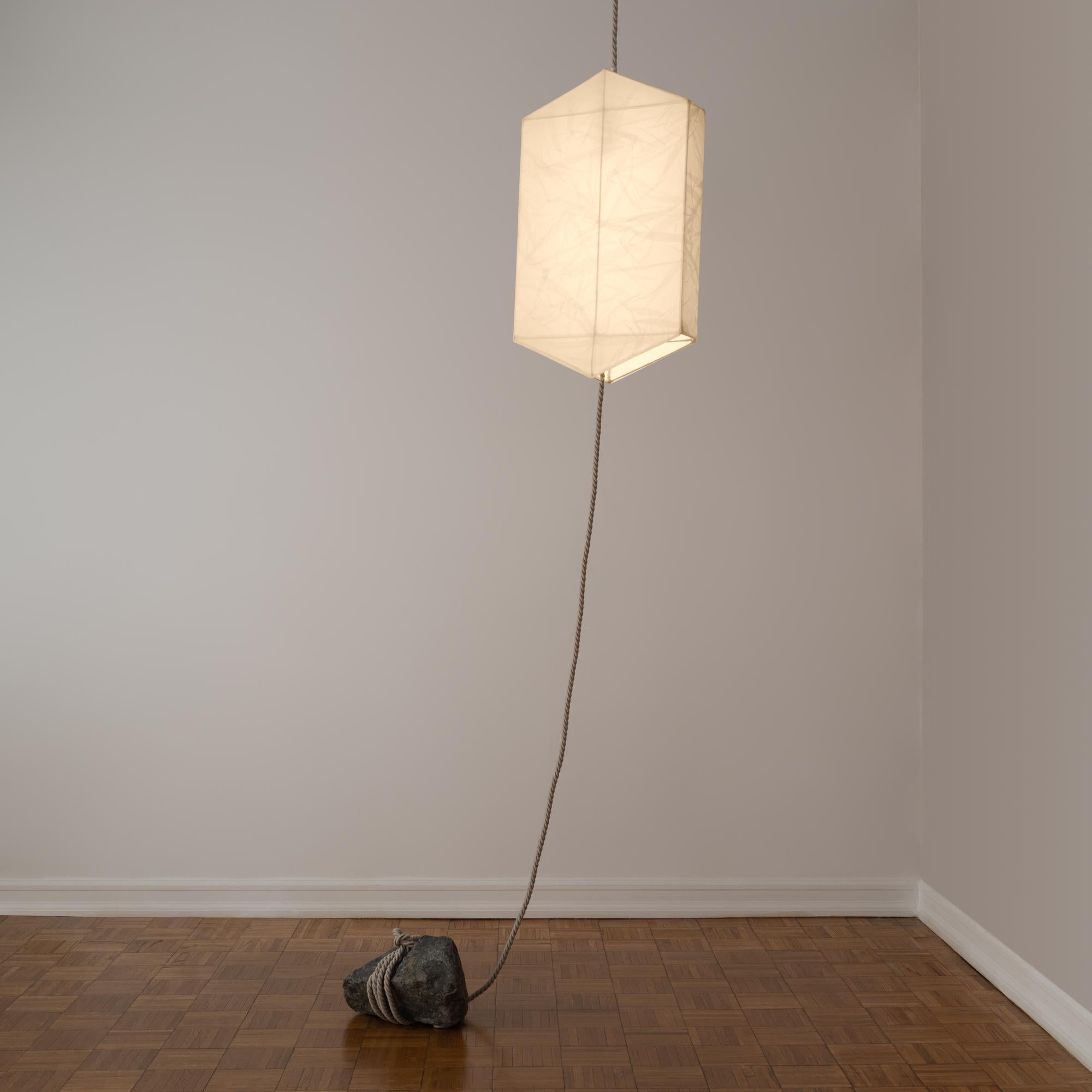Lampe suspendue unique en son genre, semblable à une lanterne, composée d'organza de soie tendu sur un cadre hexagonal en fil d'acier, fixé au plafond par une corde et ancré au sol par une pierre. Conçue par Rafael Prieto en tandem avec l'artiste et