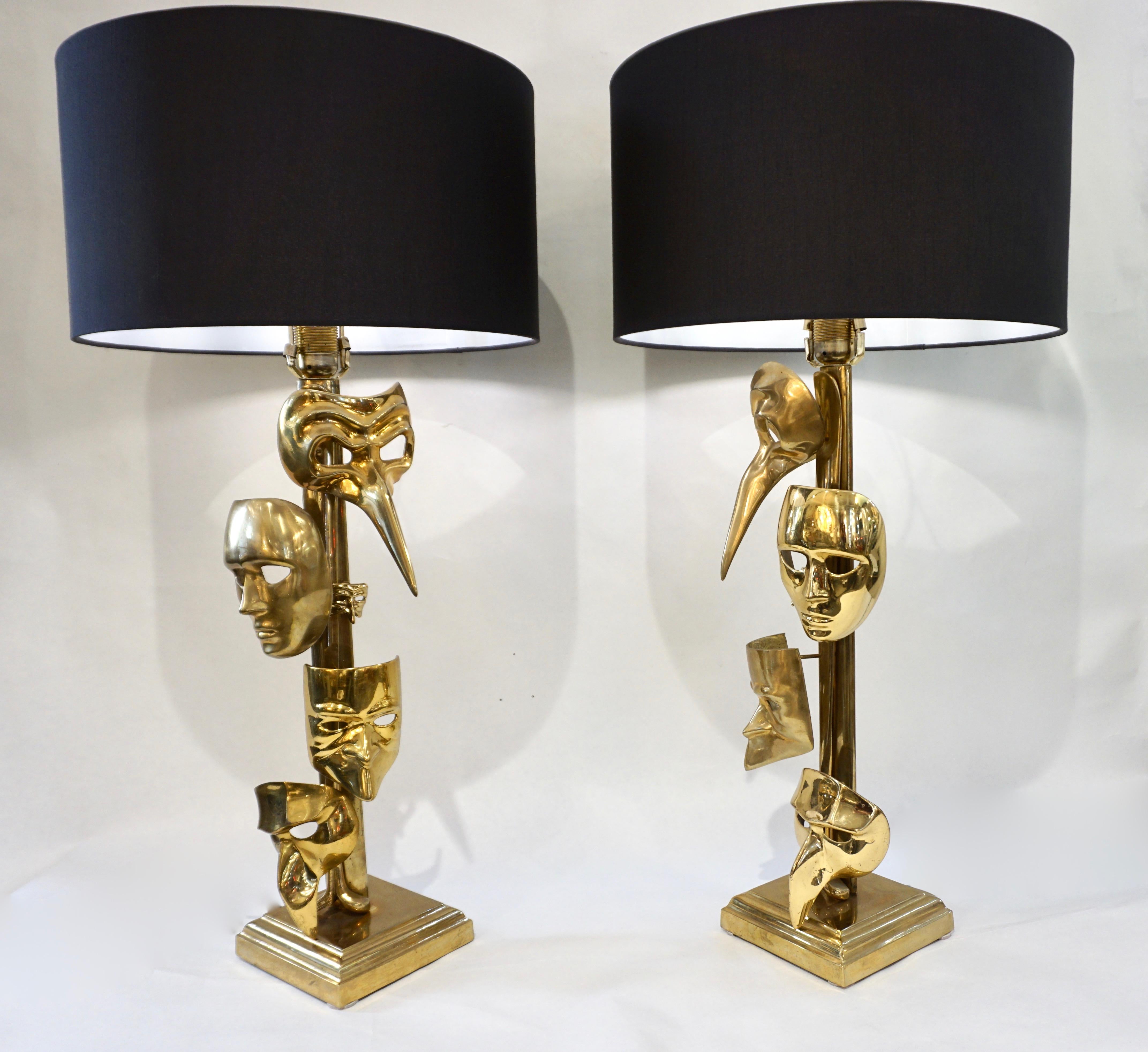 1980s vintage Italian pair of very rare lamps, entirely handmade in cast polished brass, uniquely decorated with carnival masks in different sizes, each different from the other, raised on a handcrafted square stepped brass base. Fitted with black