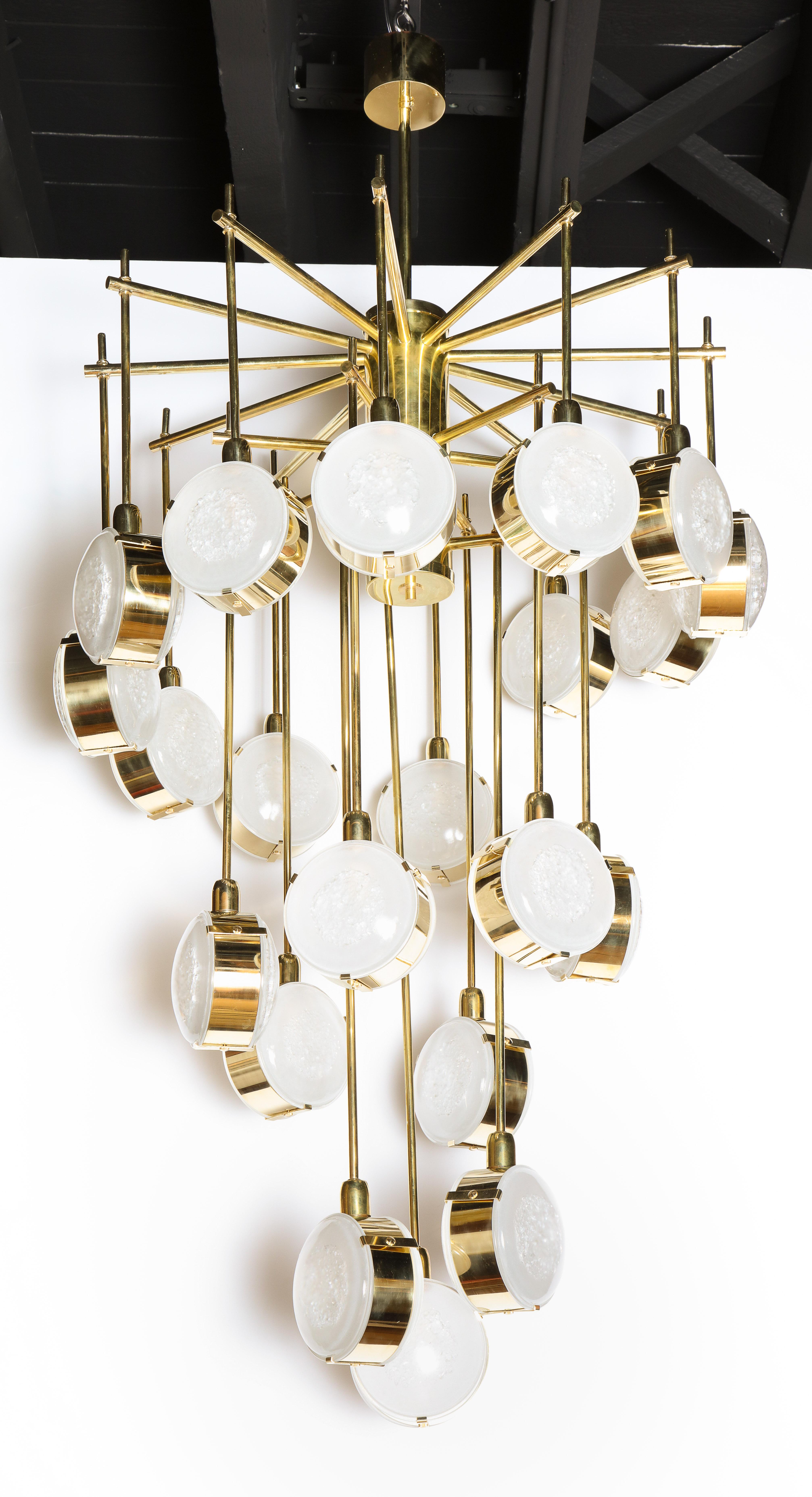 In the spirit of Max Ingrand, this cascading chandelier is made of solid natural brass rods that turn and cascade like a spiral staircase. Double sided texture opaque Murano glass globes or discs are attached at the end of each rod. Inside each