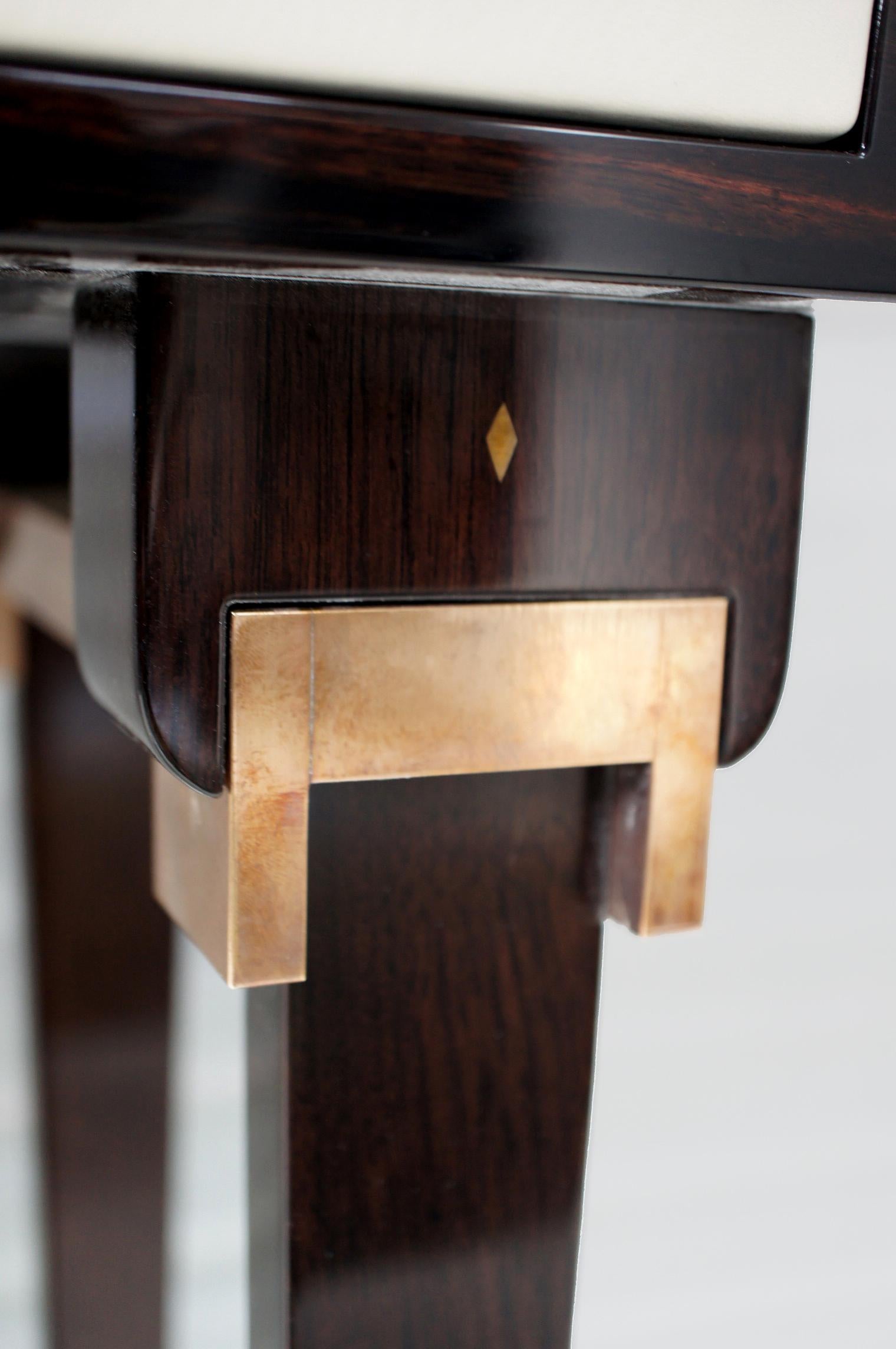 With its simplicity and elegance the Amber Console is handcrafted in Macassar, supported by ebonized English walnut and antique brass detailing. It features a distinctive central wooden panel which is decorated with Macassar inlay in a playful