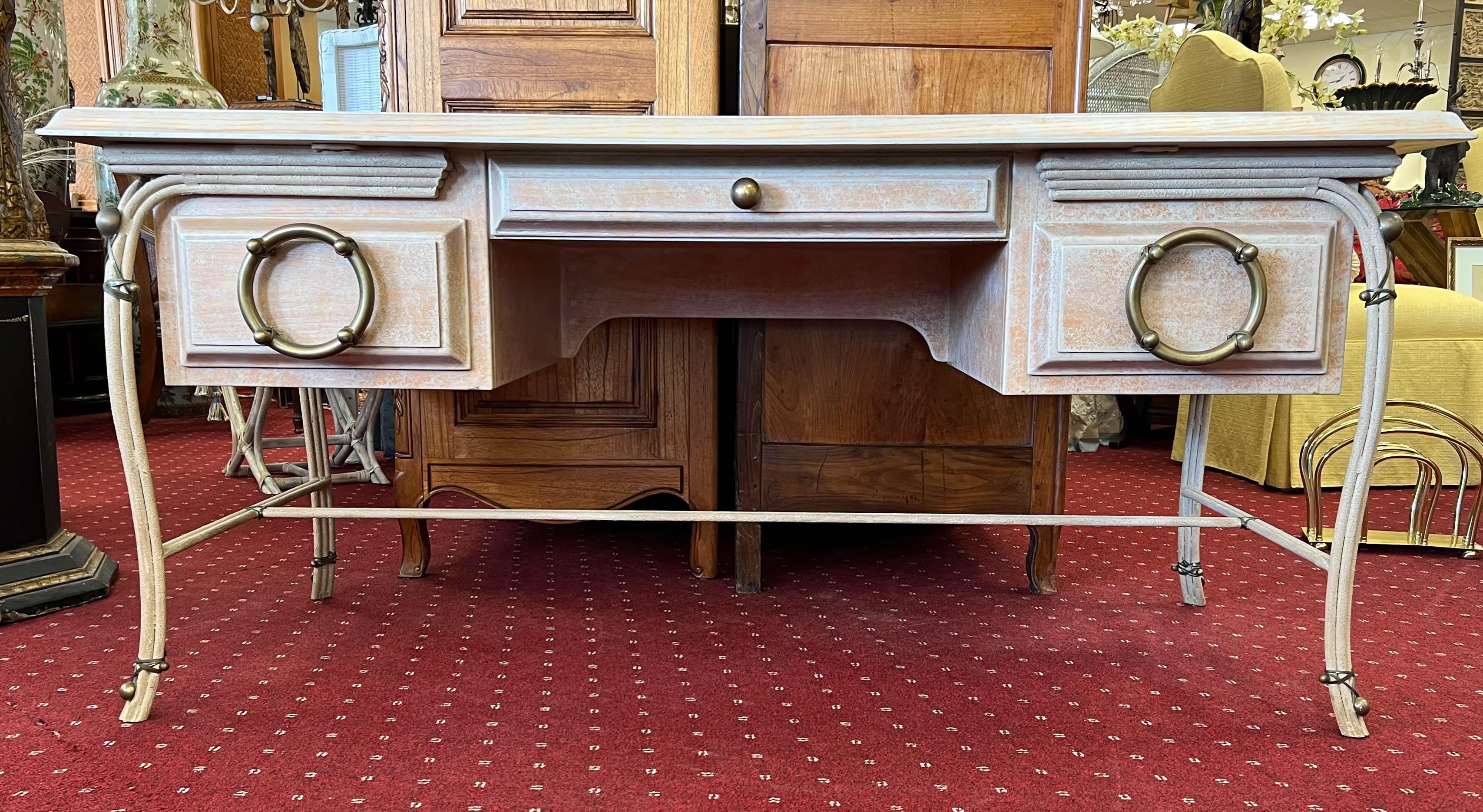 This desk harmoniously combines the strength of metal with the warmth of wood, creating a captivating juxtaposition of textures and hues. Features, such as the oversized brass ship wheel drawer pull and metal-wrapped accents, add character and lend