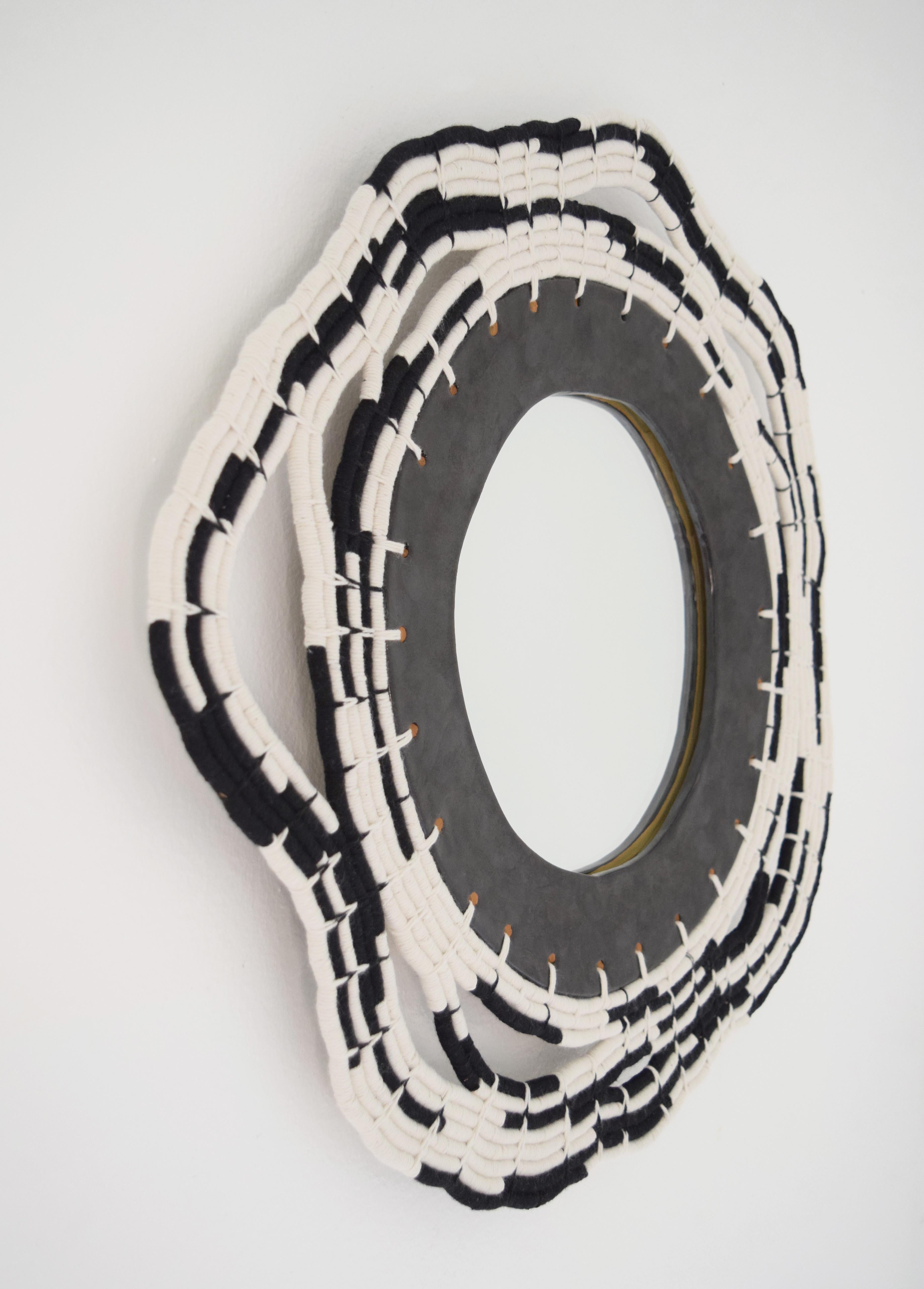 One of a kind mirror #713 by Karen Gayle Tinney.

Decorative mirror with hand formed stoneware frame glazed in satin black. The frame exterior is woven in black and white cotton, using a coiling technique which is a signature technique of the