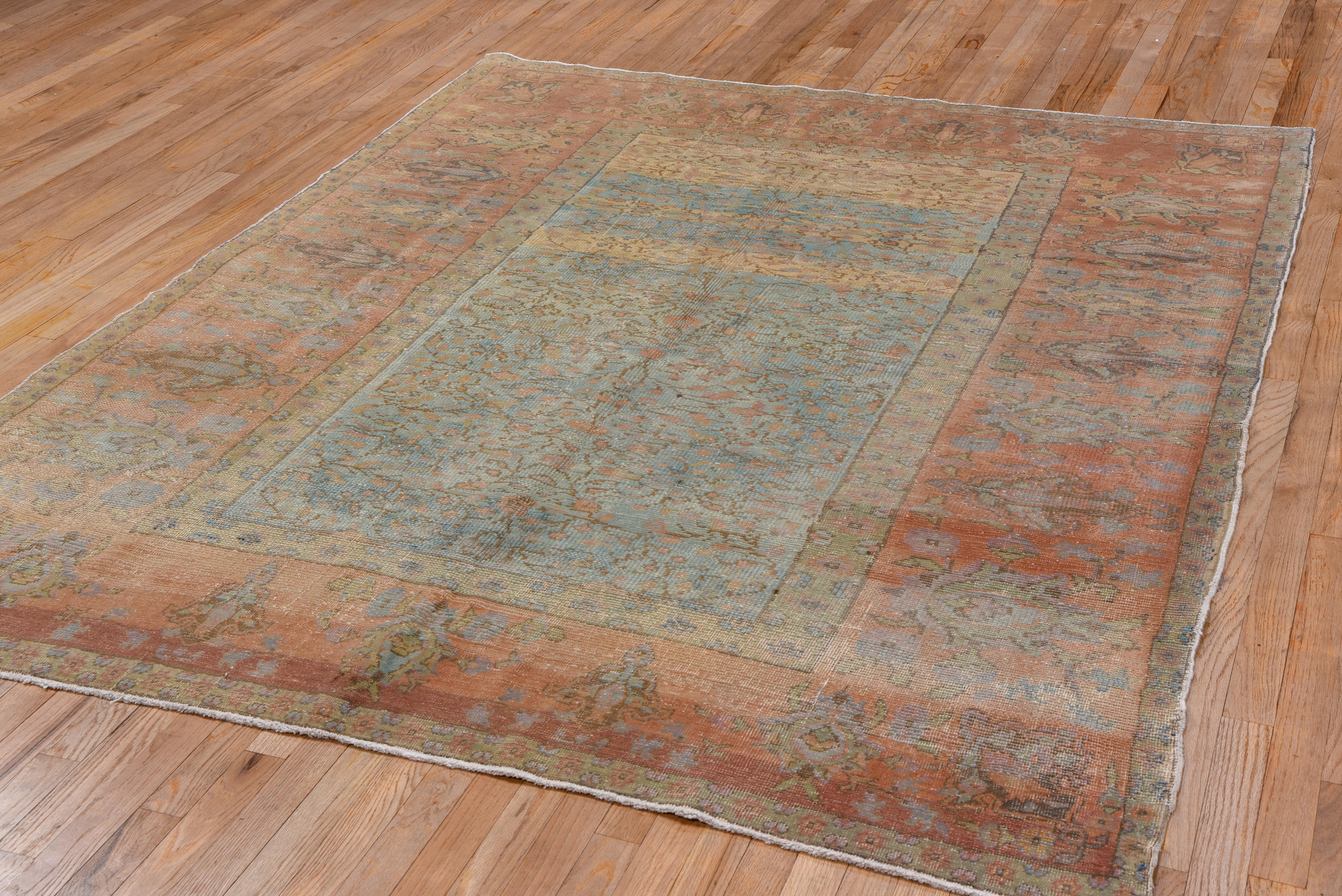 Sandy field with a wiry brown vinery pattern, set within a coral border of various palmettes with a generally subdued palette. Gorgeous pastel colors on this Oushak rug.