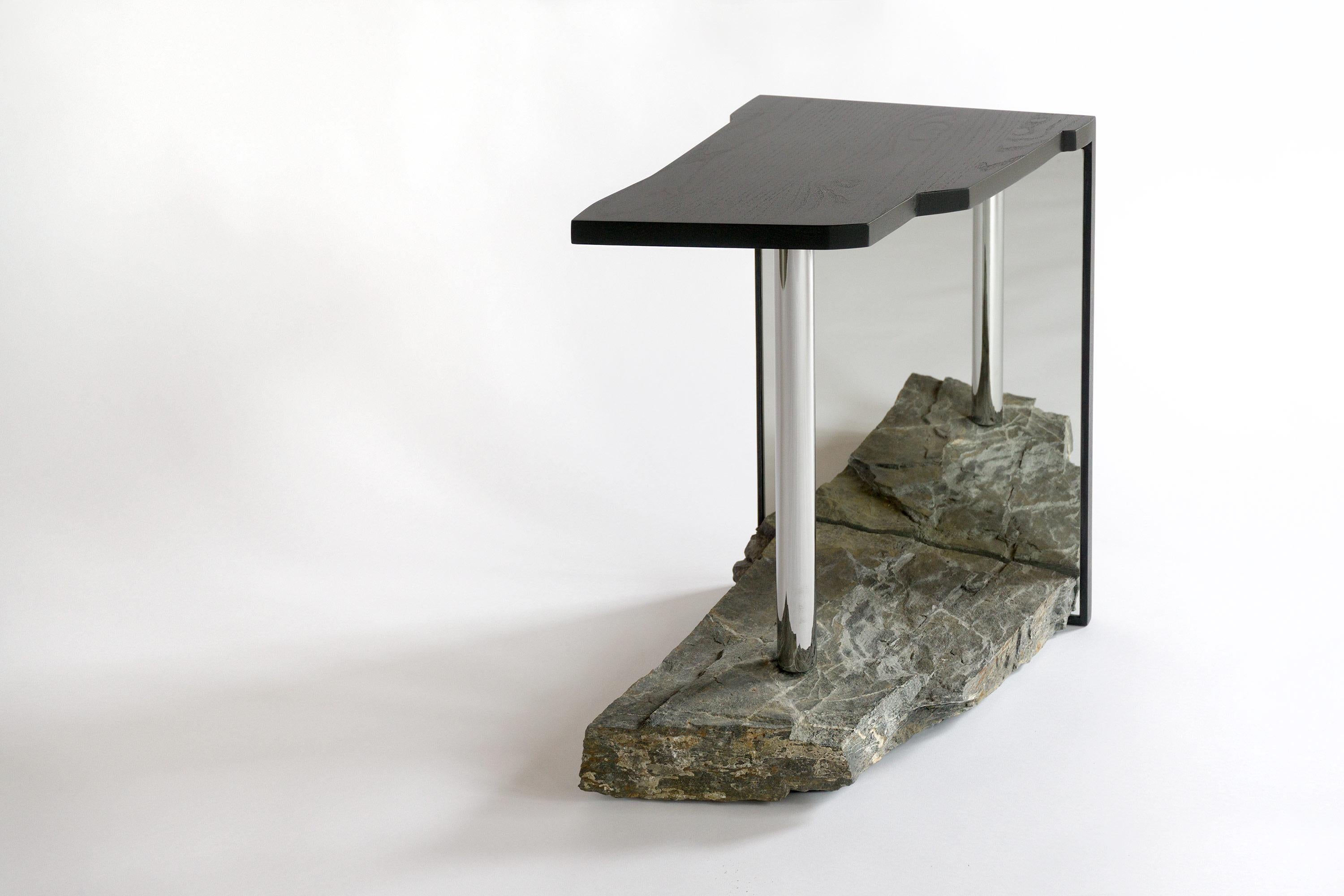 Le Missisquoi №11 intègre une pierre dont le contour et les caractéristiques ont été tracés et façonnés dans le plateau de la table, planant au-dessus d'elle pour refléter ses origines. Une illusion d'air et d'infini est créée par le reflet qui