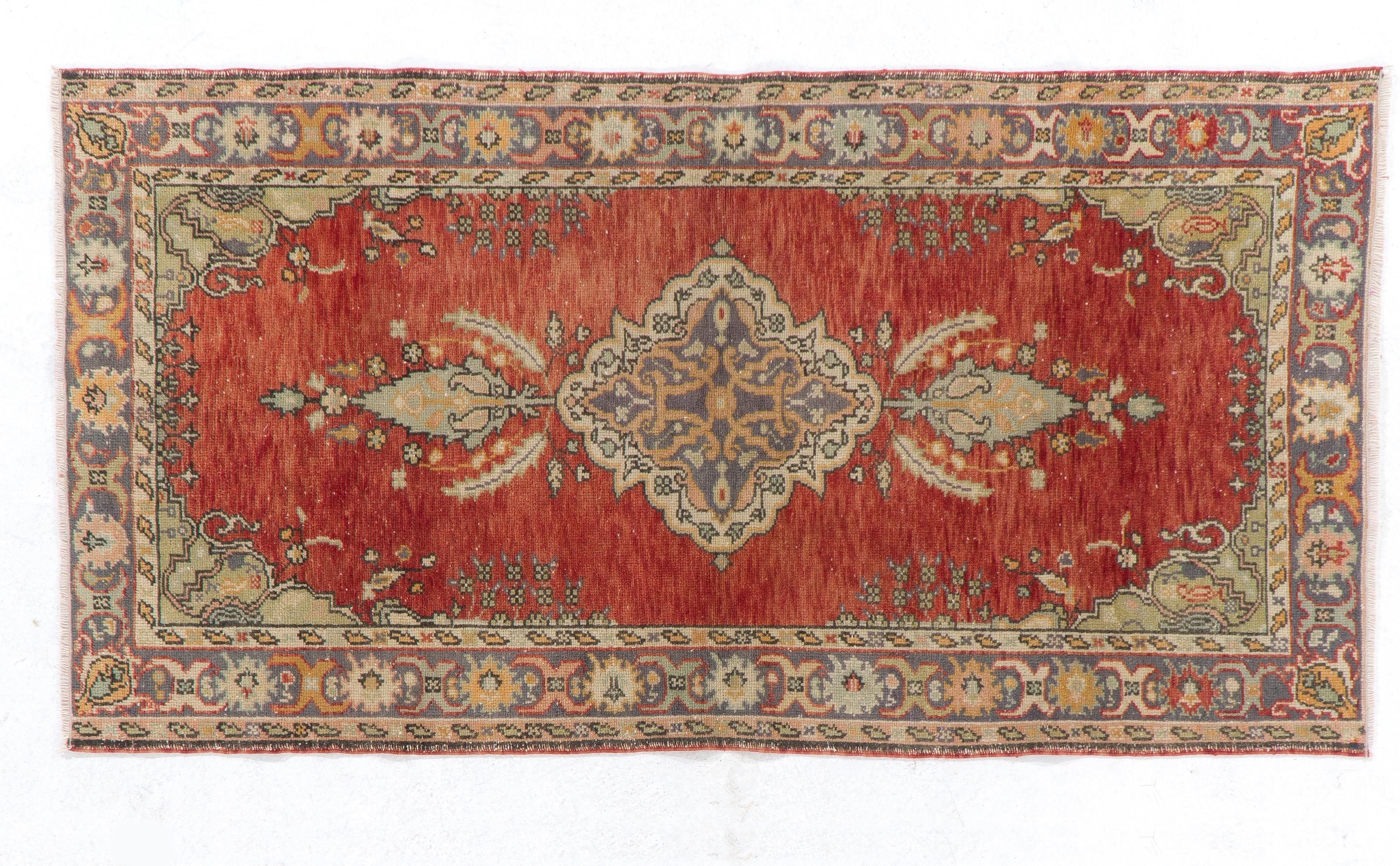 This vintage hand knotted rug features a central medallion in cream and slate blue at the centre of a field in warm red surrounded by a main border in slate blue decorated with palmettes and angular leaves.

This rug has low wool pile on cotton