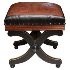 L'un des deux poufs assortis à structure en X, recouverts de cuir