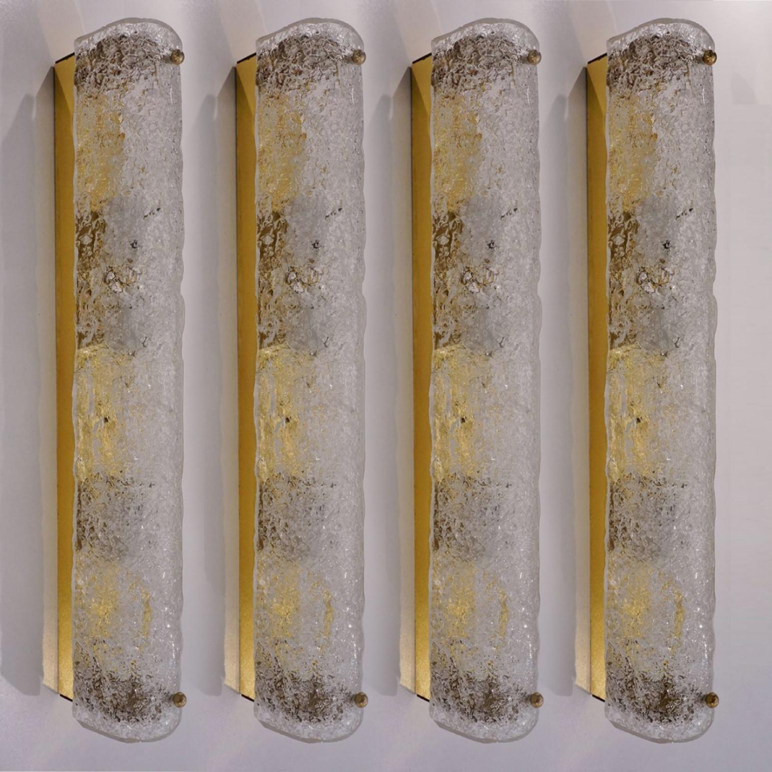 L'une des quatre appliques haut de gamme en verre de Murano sur base en laiton de Hillebrand, Allemagne, vers les années 1960. Il est composé d'un abat-jour tubulaire en cristal clair de qualité texturée simulant la glace sur un cadre en laiton. Le
