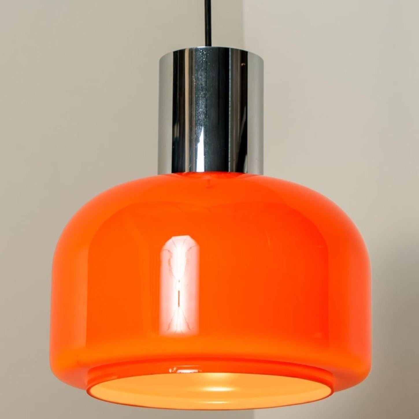 There’s something about orange that screams this particular era. And this 1970s pair of Peill & Putzler ceiling pendant lamps is very orange!
With chrome details a black cord and canopy.

The lovely shaped hand blown lampshade is made of a ‘cast