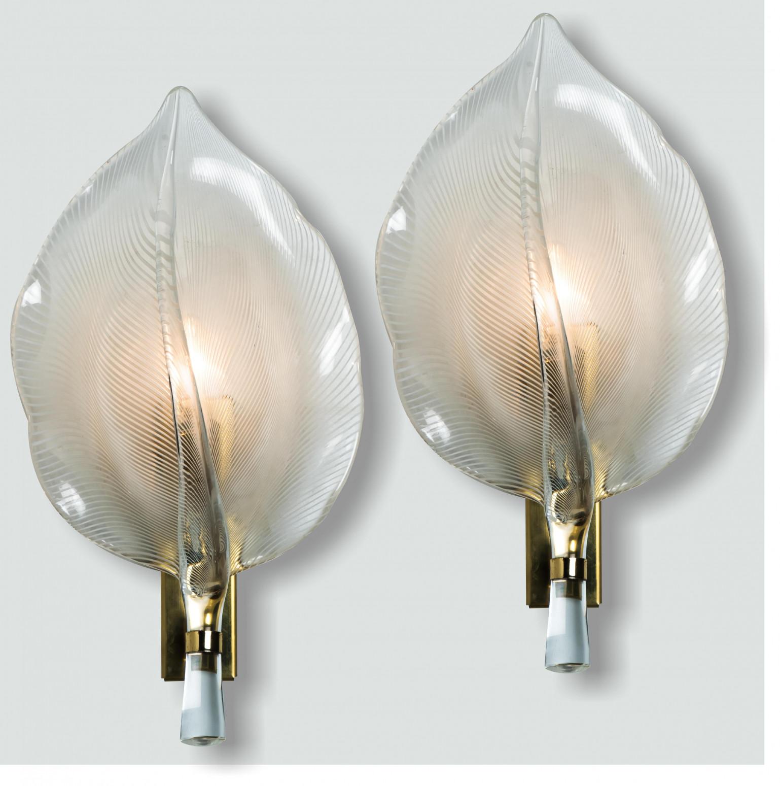 Apliques de hojas estriadas de cristal de Murano soplado a mano, diseñados por Franco Luce, Italia, hacia la década de 1970. Cada pieza presenta delicadas hojas de cristal montadas en un marco de latón, que refractan la luz para crear un resplandor