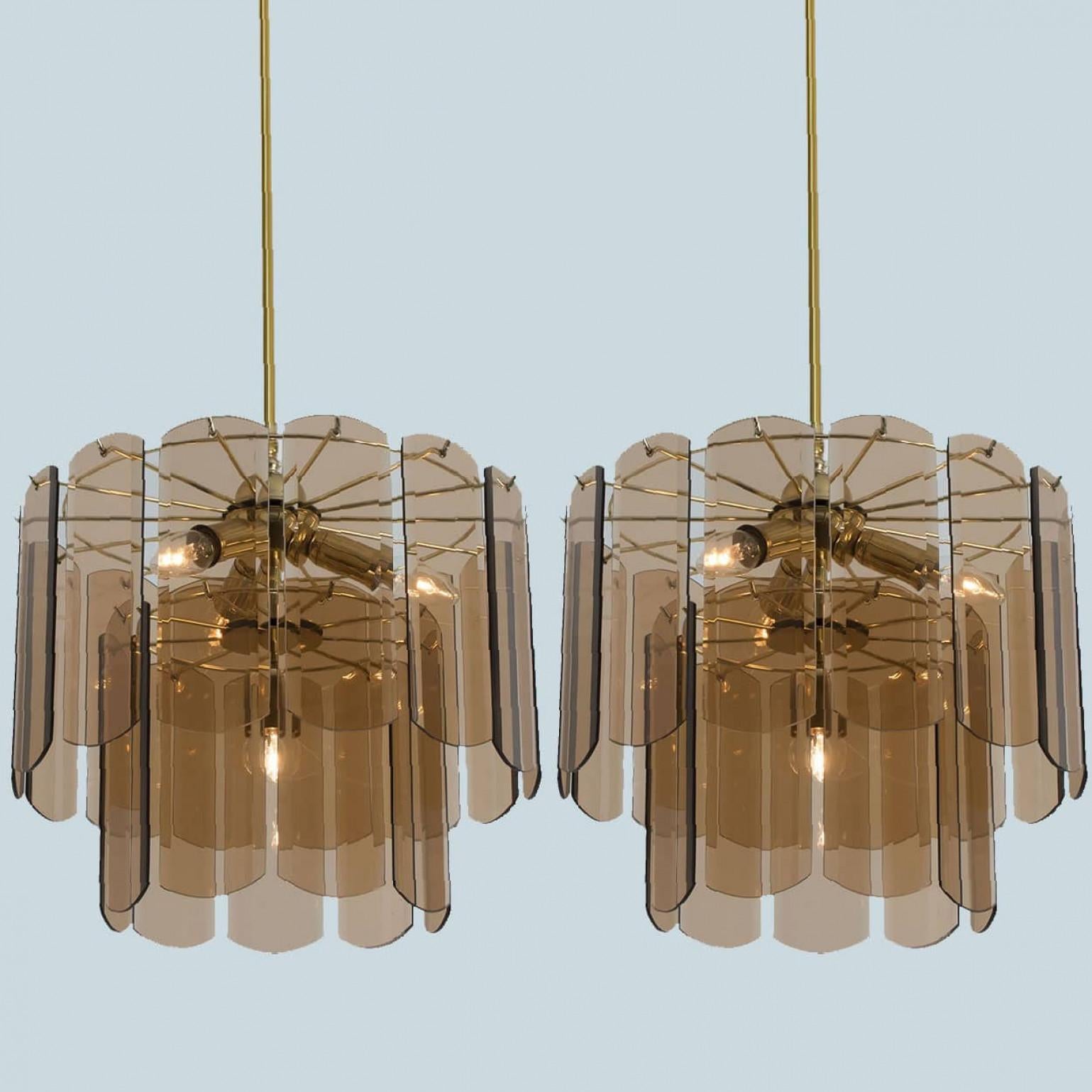 L'un des deux superbes luminaires suspendus, Allemagne 1970. Le luminaire présente un cadre en laiton entièrement doré orné de deux couches de plaques de verre fumé, mettant en valeur un design géométrique saisissant qui diffuse magnifiquement la