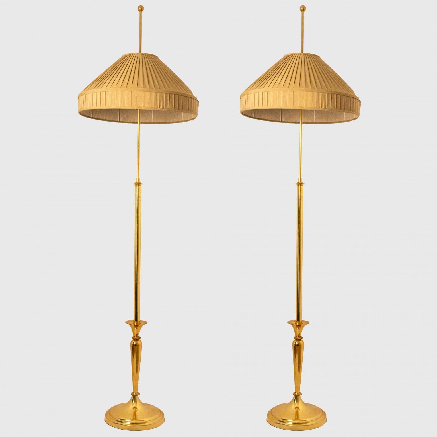 Classic Floor Lamp with Brass Base and modern twist,  Germany 1960.

The relatively large fabric shade, characterized by a subtle slope and a straight vertical edge at its end, was also common for the time, but it was usually decorated with fringes