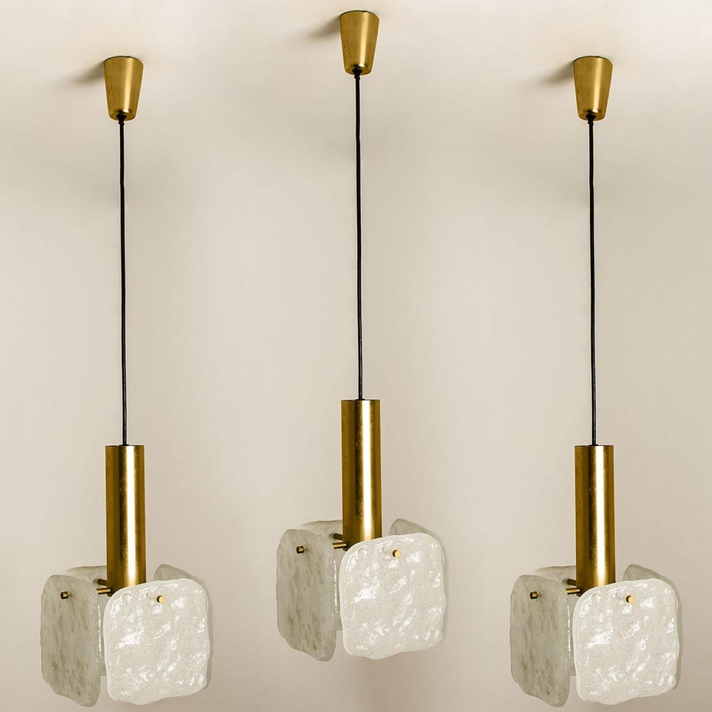 Una delle tre lampade a sospensione in vetro di ghiaccio disegnate da J.T. Kalmar, prodotte da Kalmar Franken, Austria, negli anni '60.
Ogni ciondolo ha quattro grandi quadrati di vetro bianco opaco testurizzato (ciascuno di circa 17 cm x 17 m) che