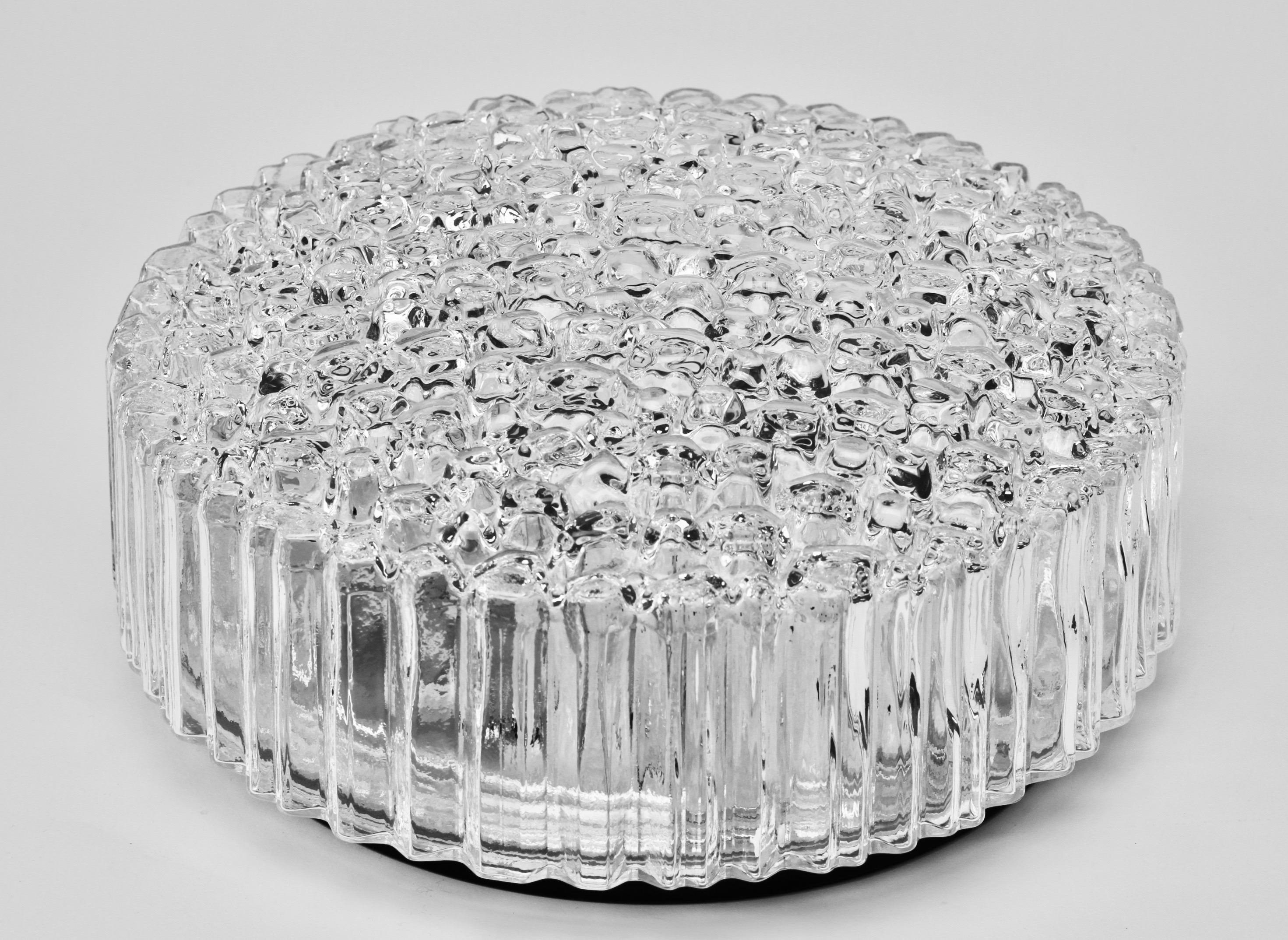 Eine von fünf flächenbündigen Leuchten oder Wandleuchtern von Glashütte Limburg, ca. 1970er Jahre. Mit ihrem wunderschönen mundgeblasenen, geformten und strukturierten Klarglasschirm, der an Eiskristalle erinnert, leuchtet diese Vintage-Lampe aus