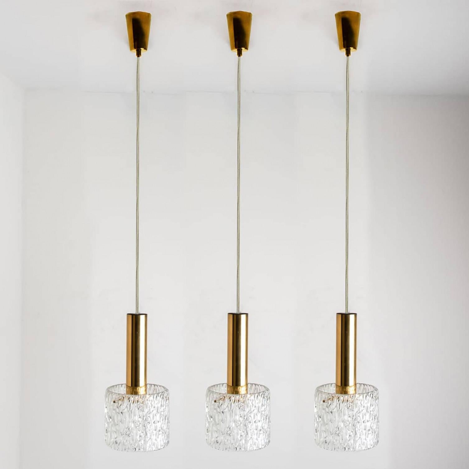 Una delle tre lampade a sospensione in vetro a onda disegnate da J.T. Kalmar e prodotte da Kalmar, Austria, negli anni '60.
Un design semplice ma bello. Ogni pendente ha un paralume in vetro testurizzato a onde su una base in ottone. Fornisce una