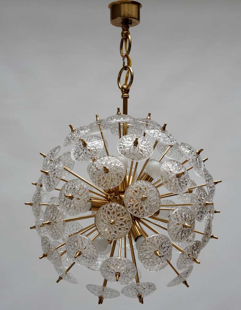 Two large scaled modernist sputnik chandeliers each featuring, polished lacquered brass frames with multiple light sources and multiple arms. On to each arm is attached a large flower shaped light diffuser in clear molded glass.

Price per item.