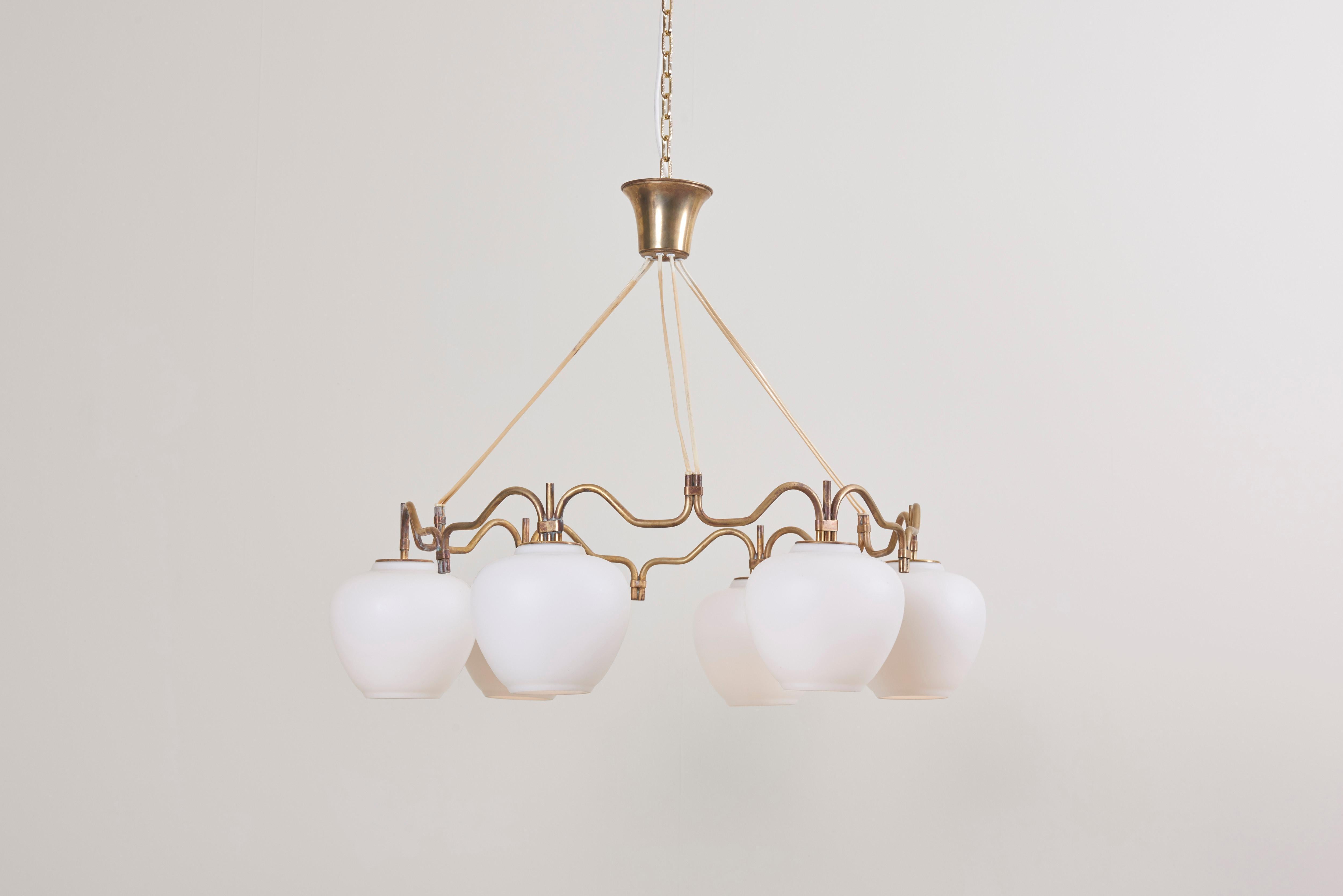 A round brass chandelier with six opaline glass shades, by Bent Karlby for Lyfa. The brass shows a beautiful patina.

To be on the safe side, the lamp should be checked locally by a specialist concerning local requirements.