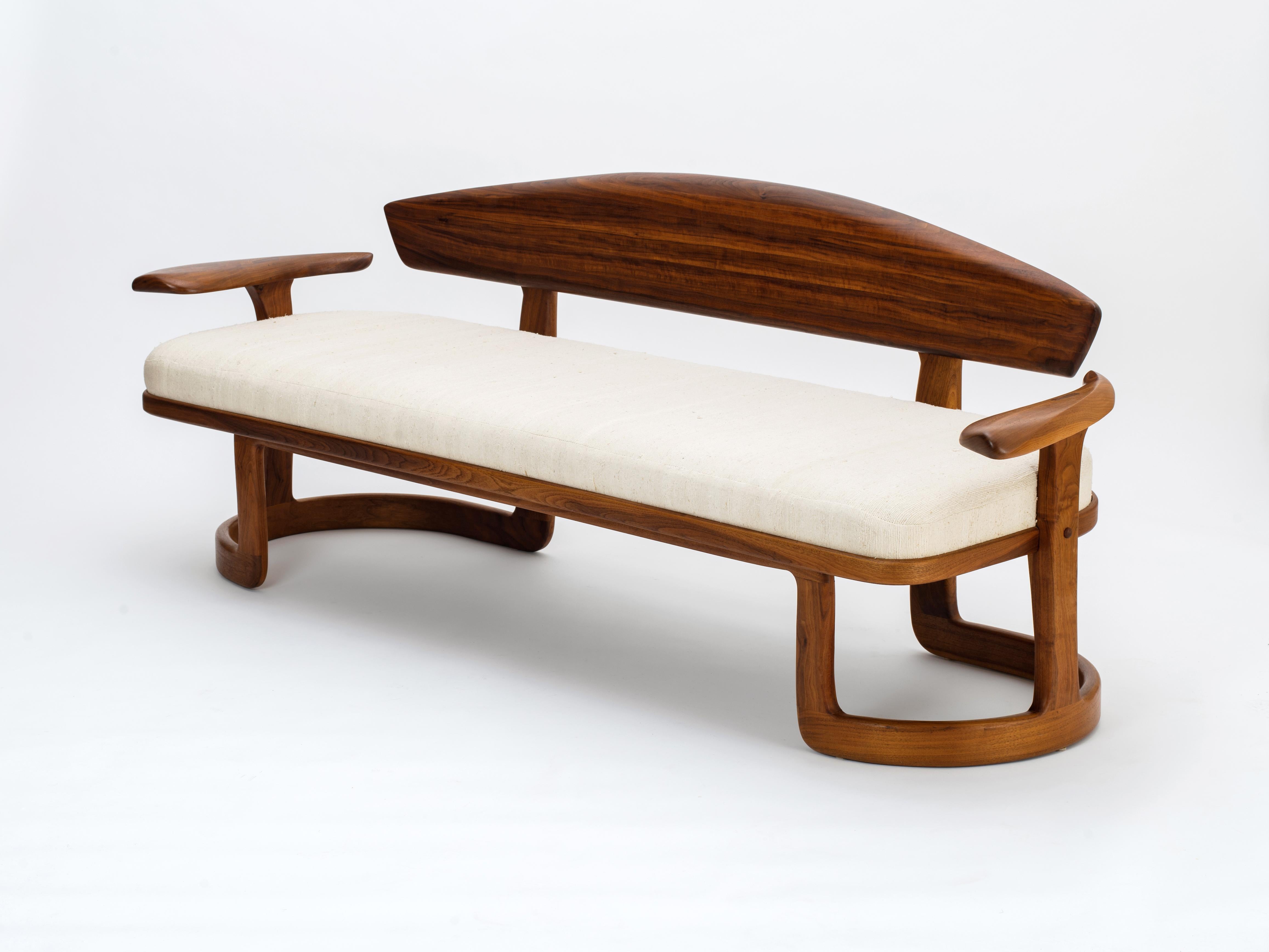 Un exceptionnel canapé Studio Craft américain exécuté en noyer noir et fini avec un coussin d'assise en soie brute, conçu et construit par Larry et Nancy Buechley, vers 1987. Cette forme hautement sculpturale comprend une base en stratifié cintré
