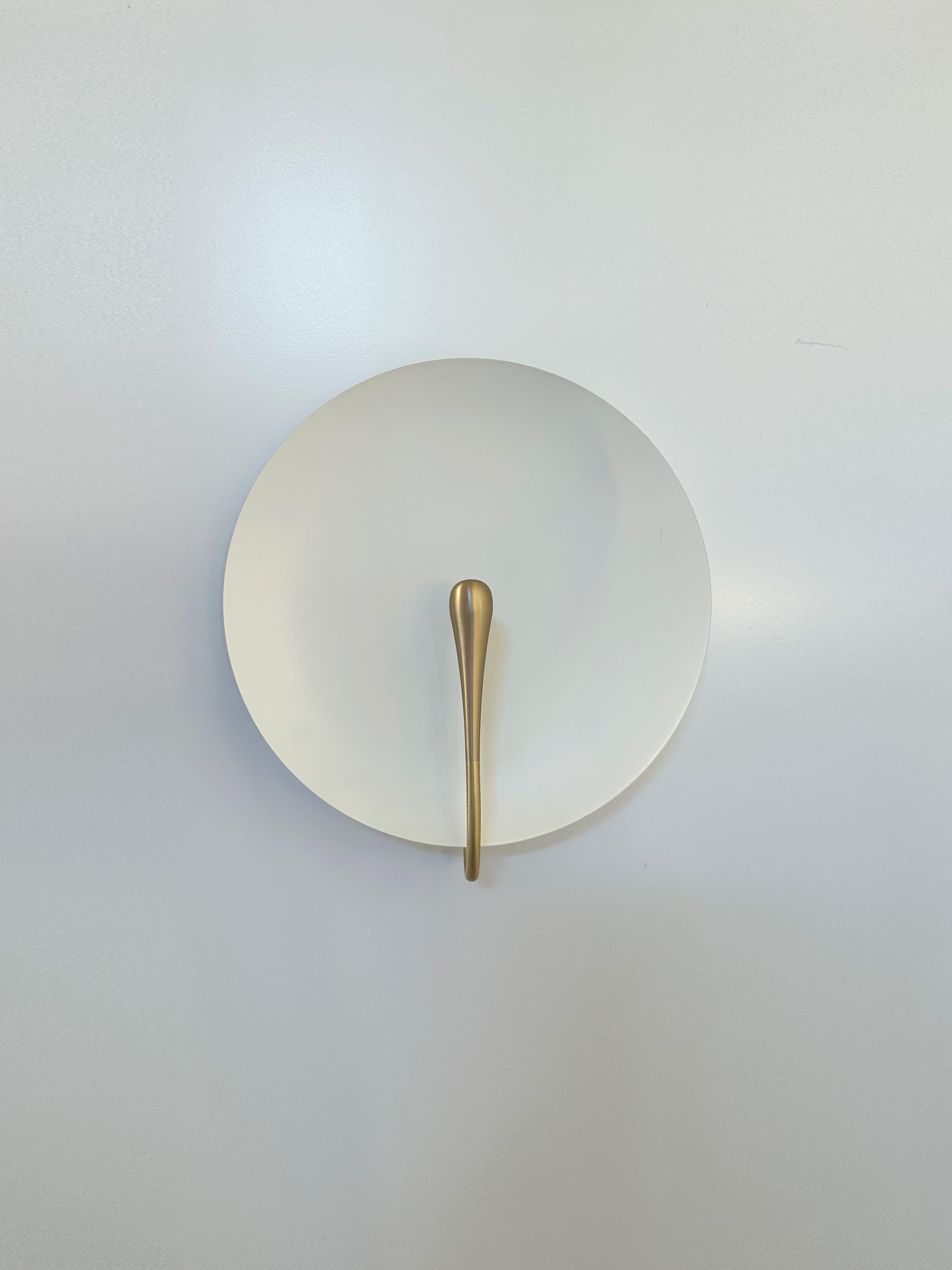 An experiment between designer and maker, this sconce is one of a kind. A matte white piano lacquer is applied to a hand-spun brass plate to create this unique finish. Each of our brass plates is hand spun in London, with each having slight
