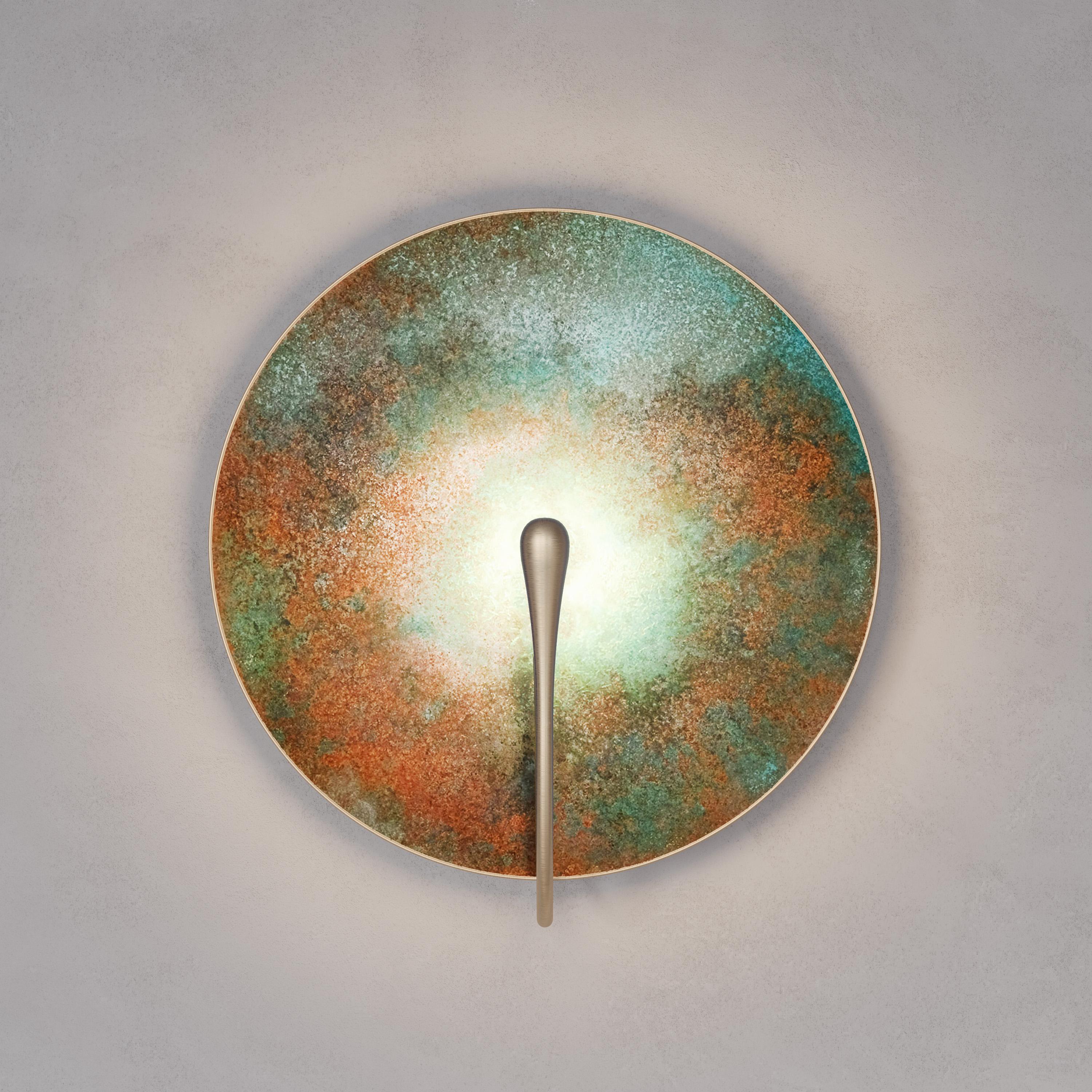 A gentle Silhouette of circular plate makes up this unique wall light. Inspired by planet-like appearances and textures, a verdigris and rust patina is applied to create this unique finish. Please note the process is slightly random and each plate