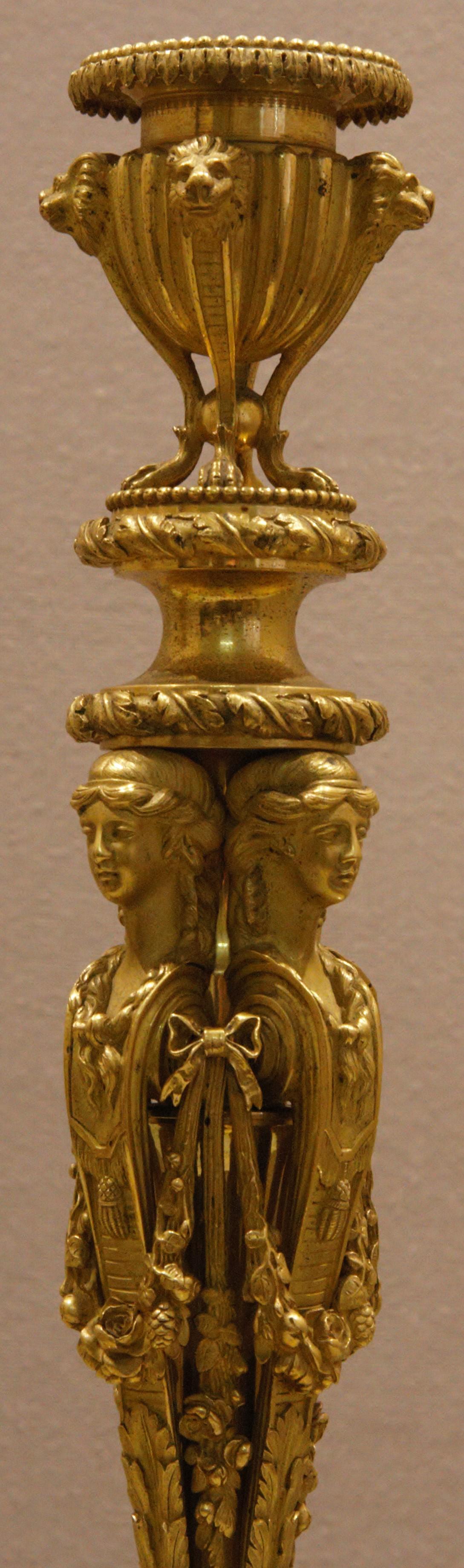 These candlesticks after design by Jean-Démonsthène Dugourc, circa 1830.
Each with addorsed female caryatids stem surmounted with stiff-leaf-cast urn-shaped nozzle and on acanthus cast domed socle and circular fluted plinth.