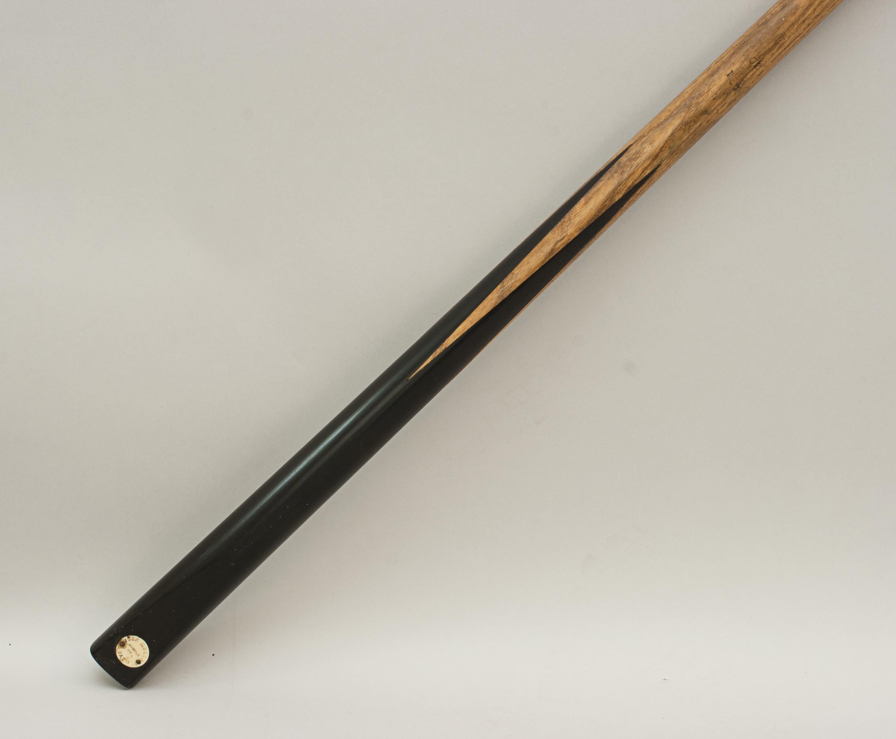John Moore billiard snooker cue.
A 58 inch one piece billiard cue. The cue is made of ash with a spliced ebony butt, the cue is stamped with the weight 15½ oz. The butt is finished with an ivorine name disc, 'John Moore, Arsyle St, Bath.'.